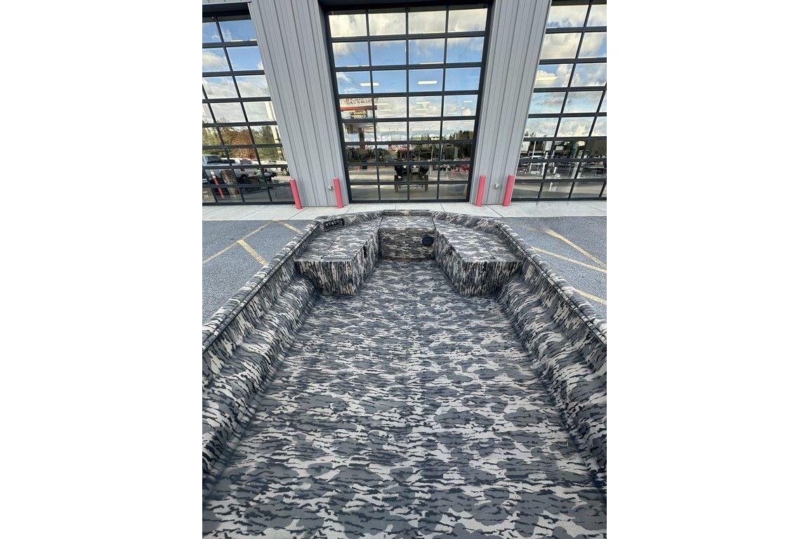 2025 Havoc 1860 boat with camouflage interior, parked outside a building with glass windows.