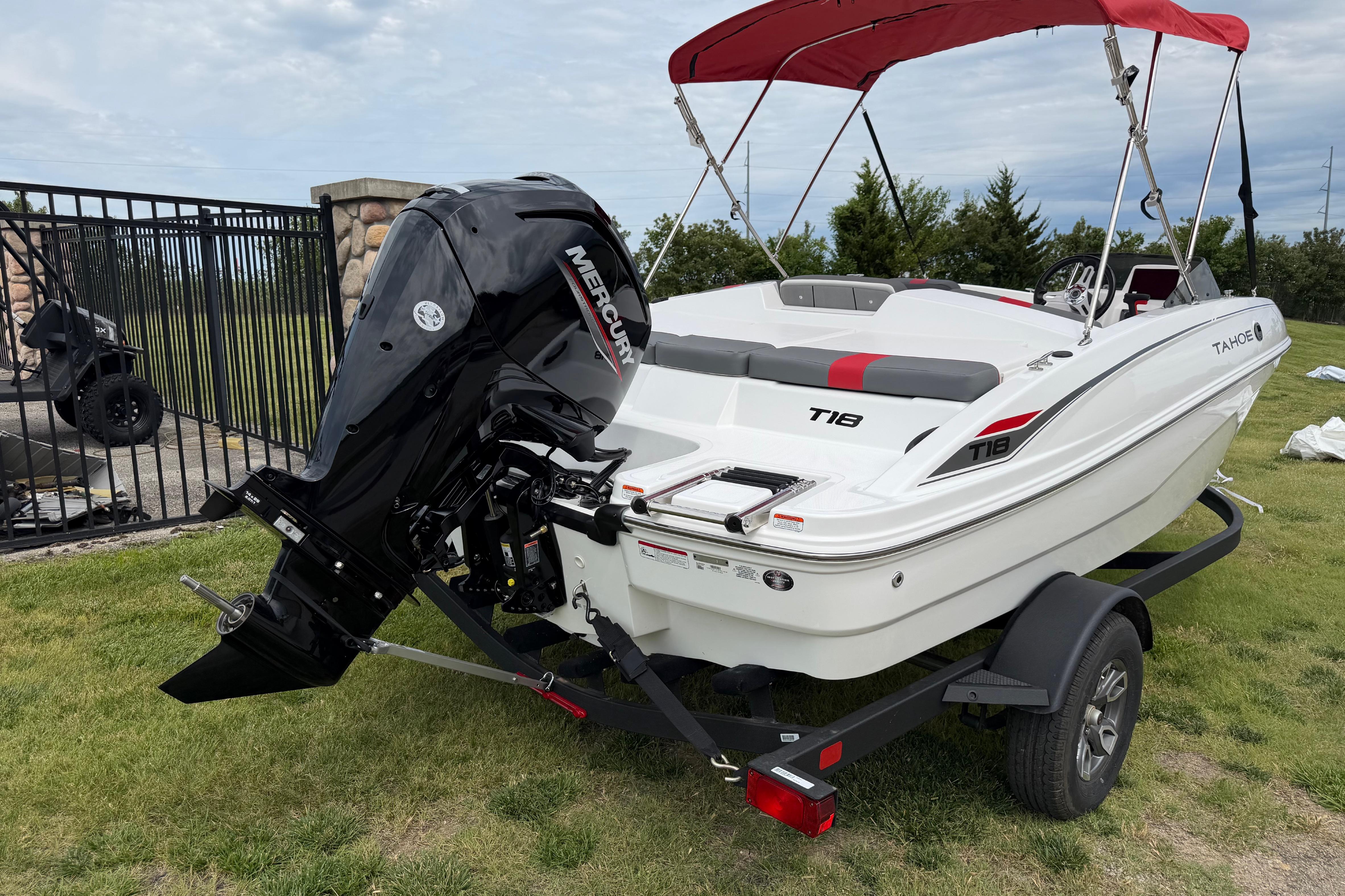 2026 Tahoe T18 boat with Mercury engine on trailer, featuring red canopy.