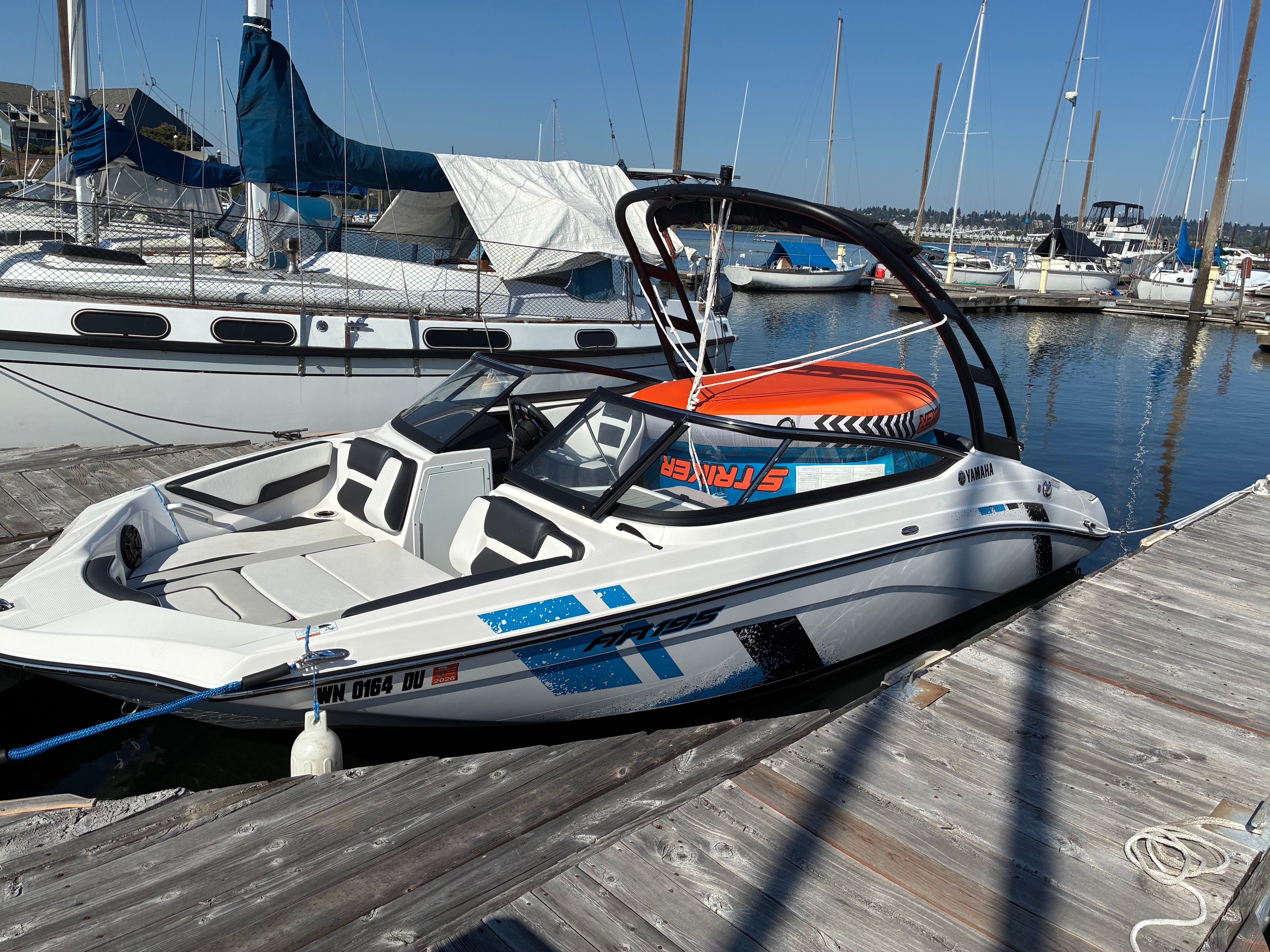 A Yamaha AR195 boat docked at a wooden pier in the harbor.