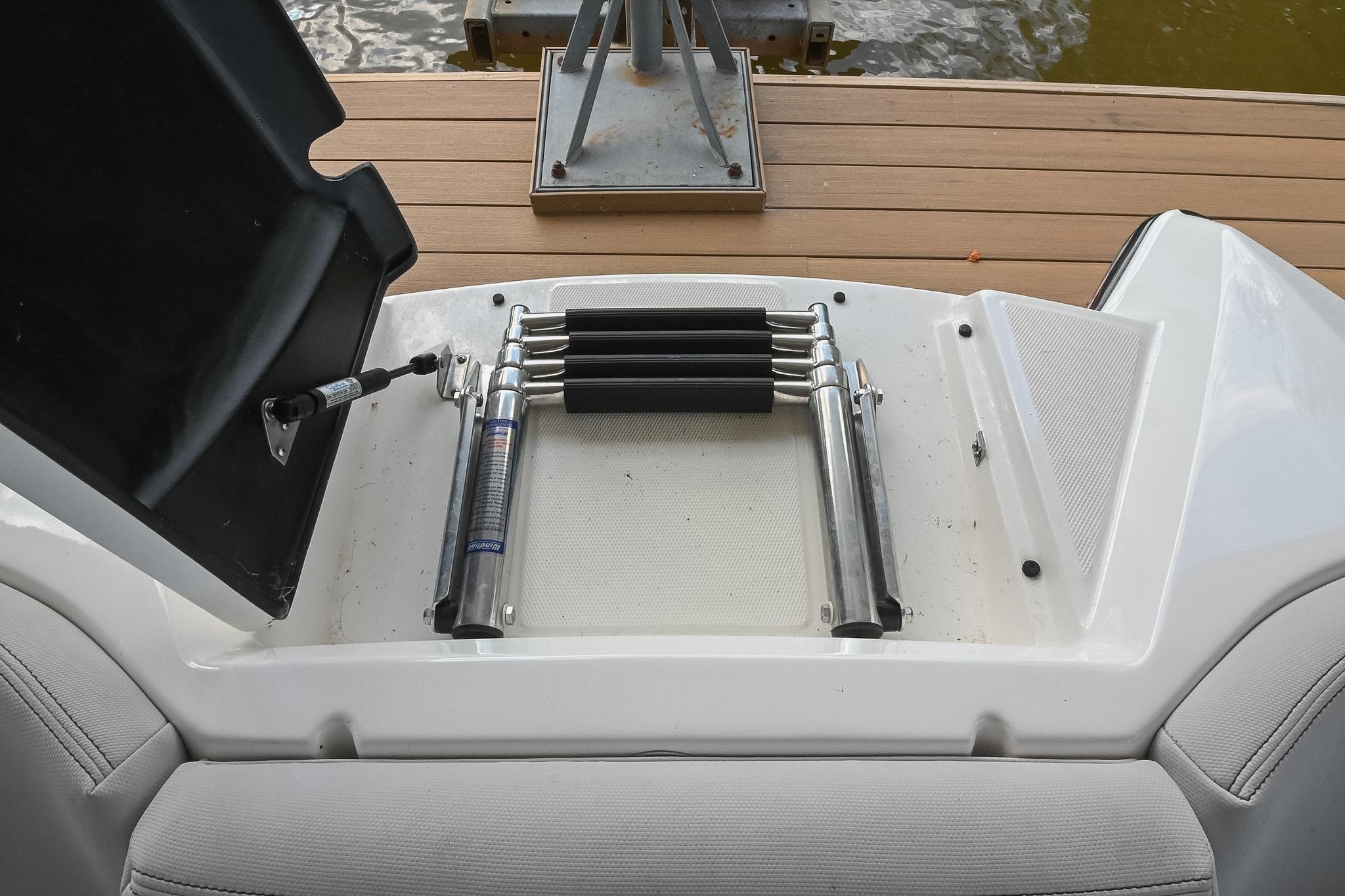 2018 MasterCraft X23 boat ladder and storage compartment on a wooden dock.