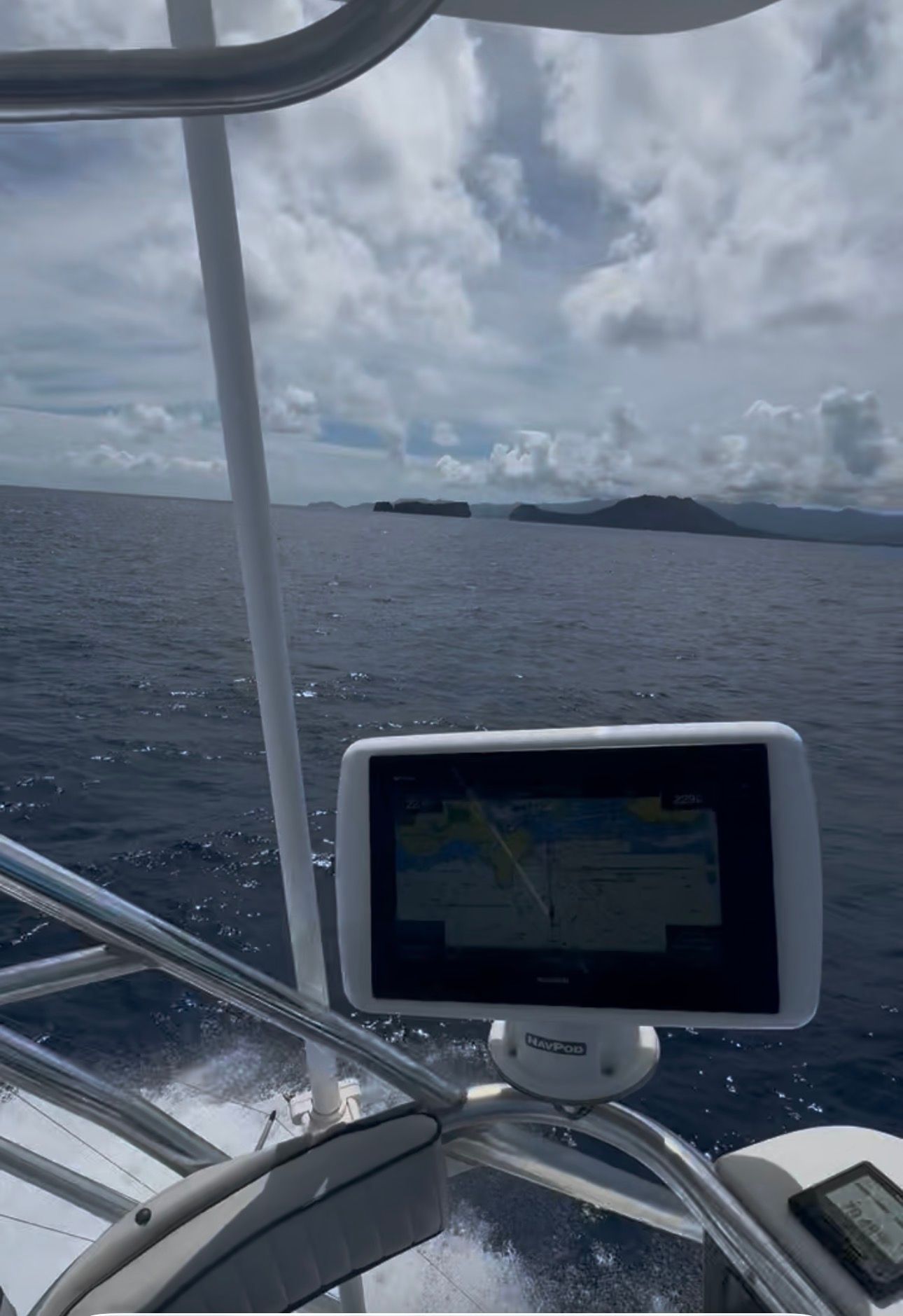 A navigation system on a boat with a view of the open sea and distant islands.