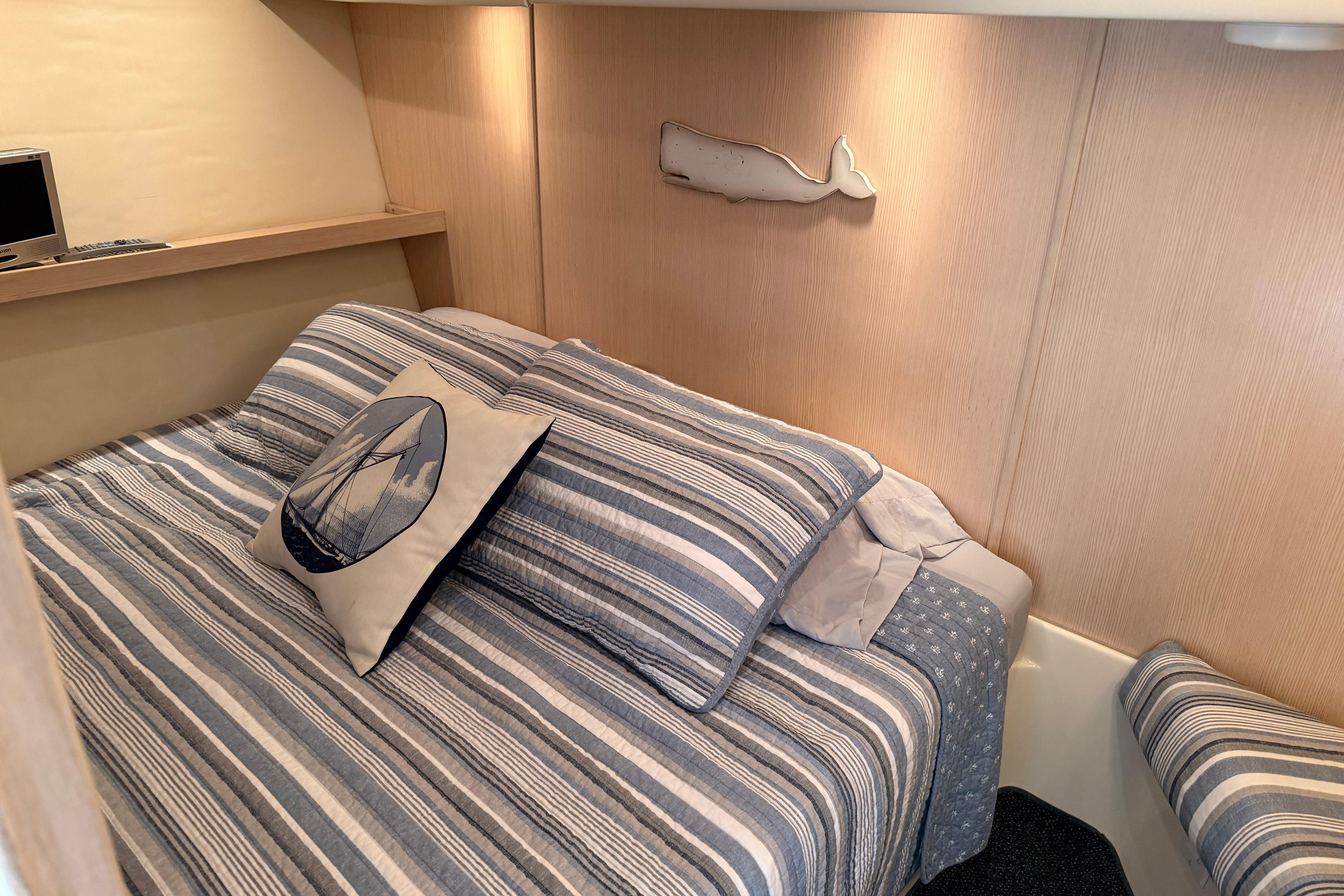 Cozy cabin interior of 1995 Tiara Yachts 4000 Express with striped bedding and nautical decor.