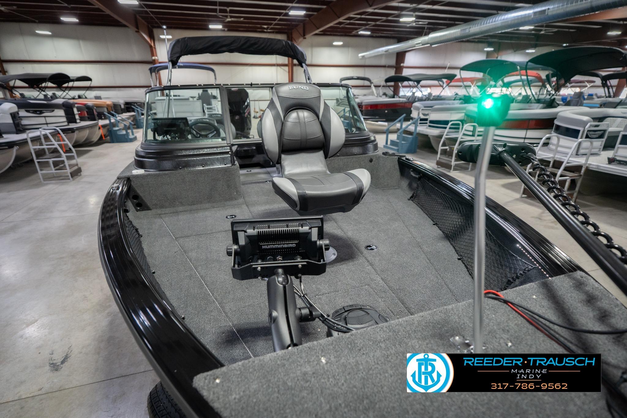 2026 Lund 2075 Impact XS boat in showroom, featuring seating and navigation equipment.