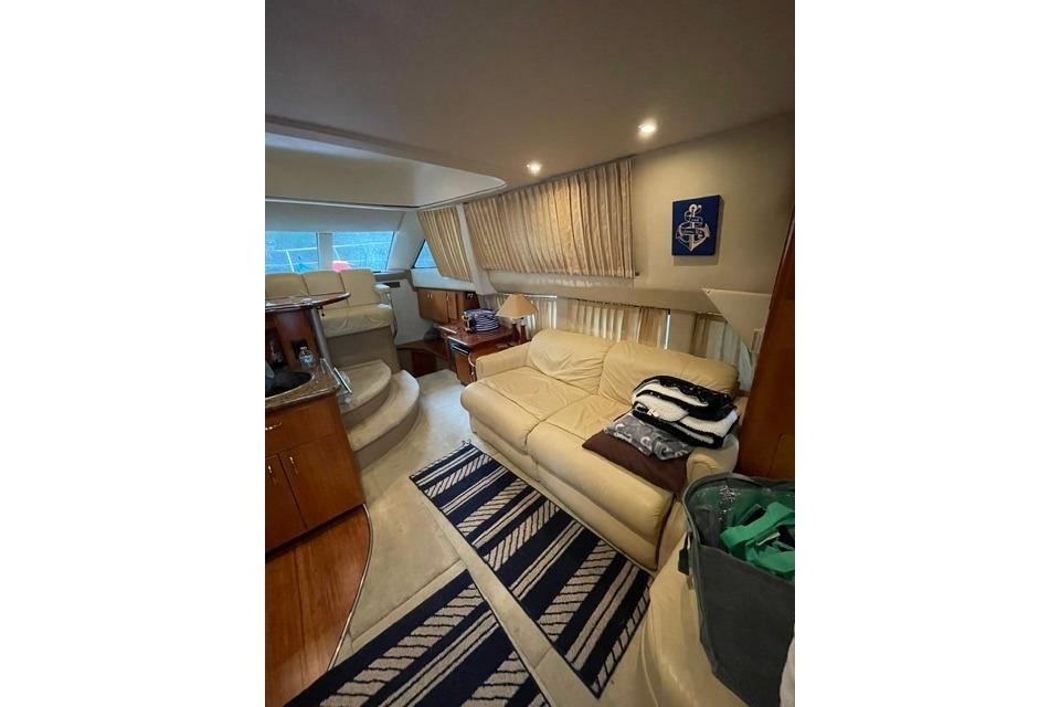 Luxurious interior of 2003 Carver 36 Super Sport yacht with beige sofa and striped rug.