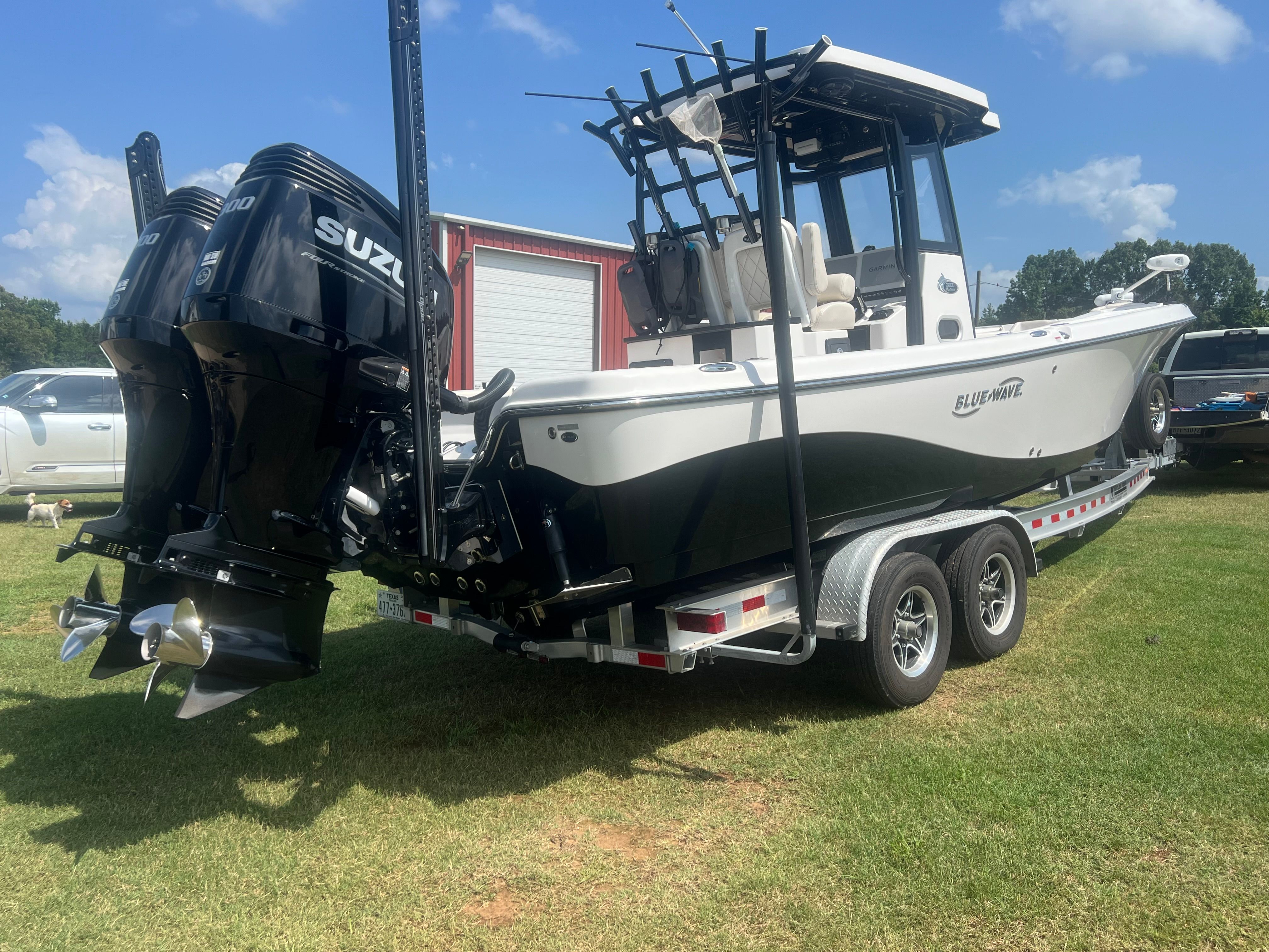 A 2023 Blue Wave 2800 Makaira boat on a trailer with dual Suzuki outboard engines.