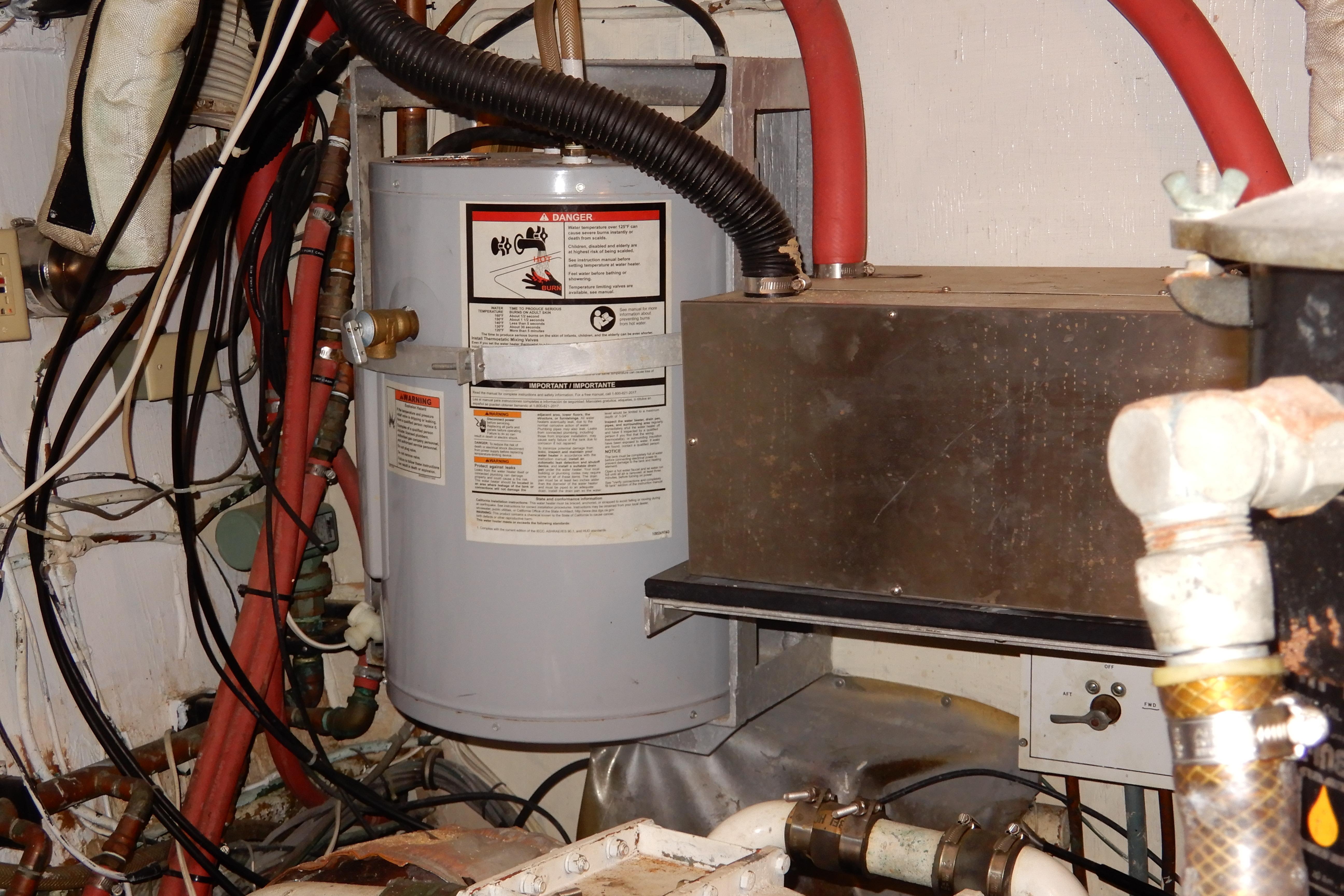 Engine room of a 1974 Hatteras 53 Motor Yacht with water heater and piping.