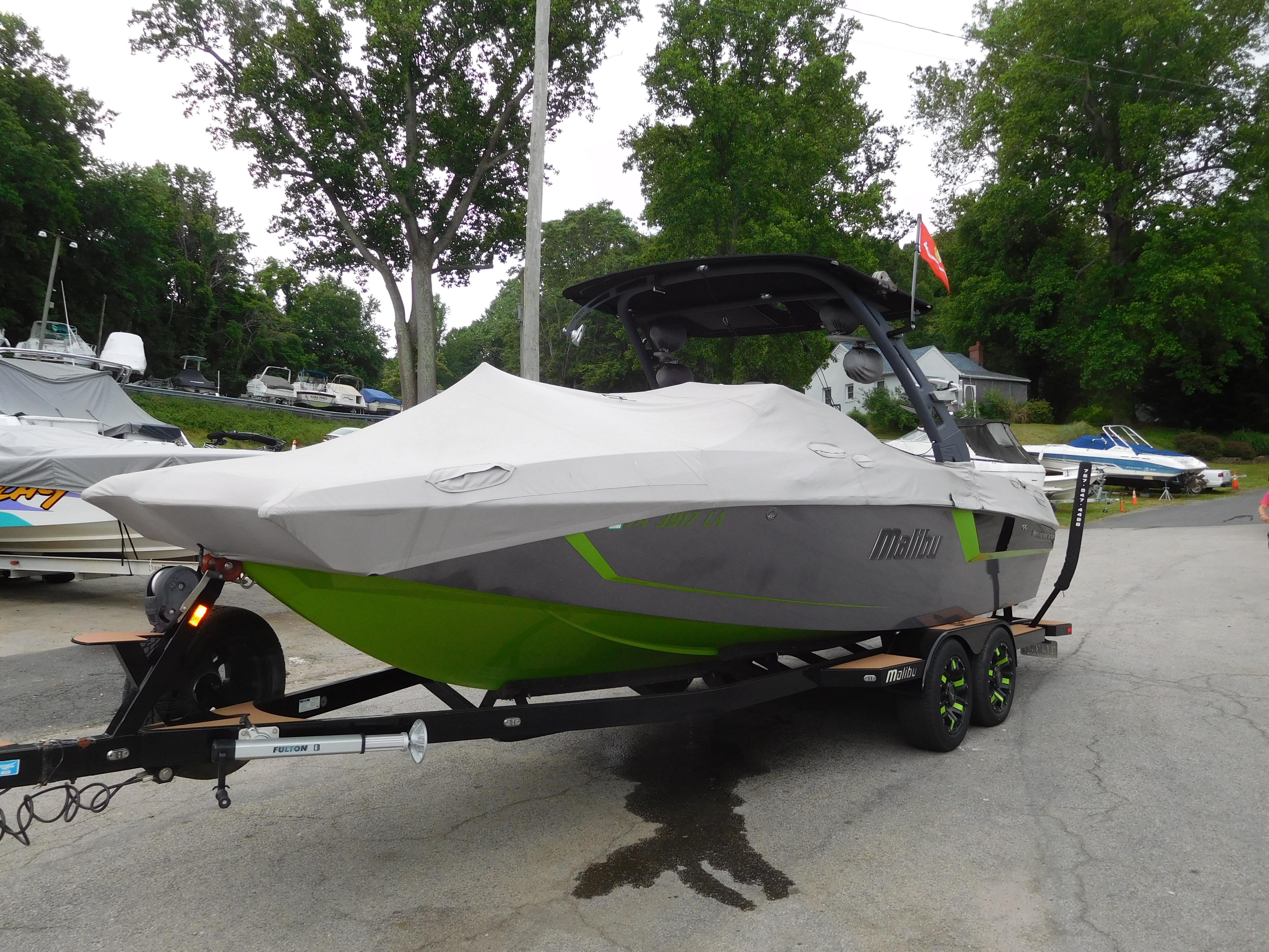 2017 Malibu Wakesetter 24 MXZ boat on a trailer, covered and parked outdoors.