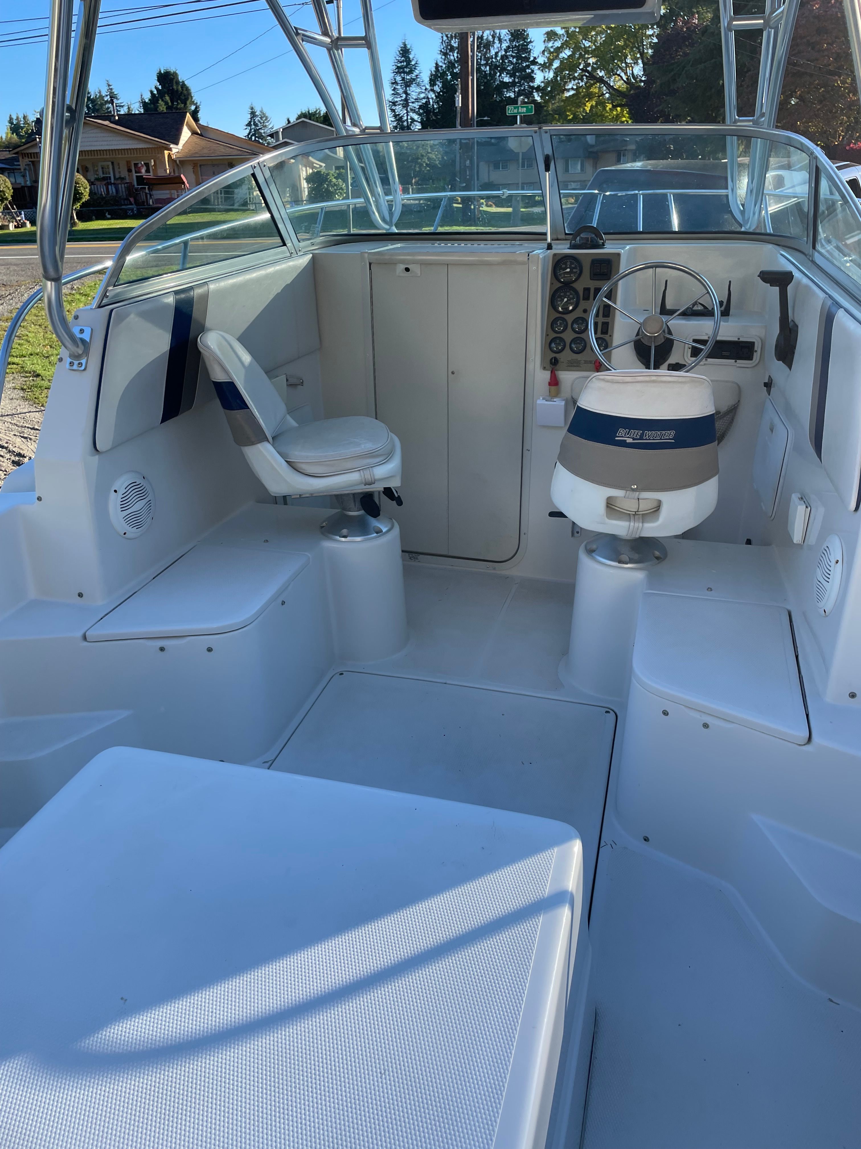 The image shows the cockpit of a 2001 Bluewater 2100 sport fisher with two seats and a helm.