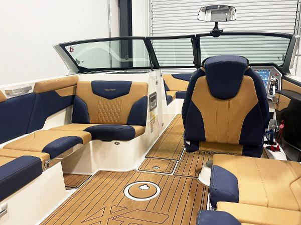 Interior of 2022 MasterCraft NXT24 boat with tan and navy seating, wood flooring.