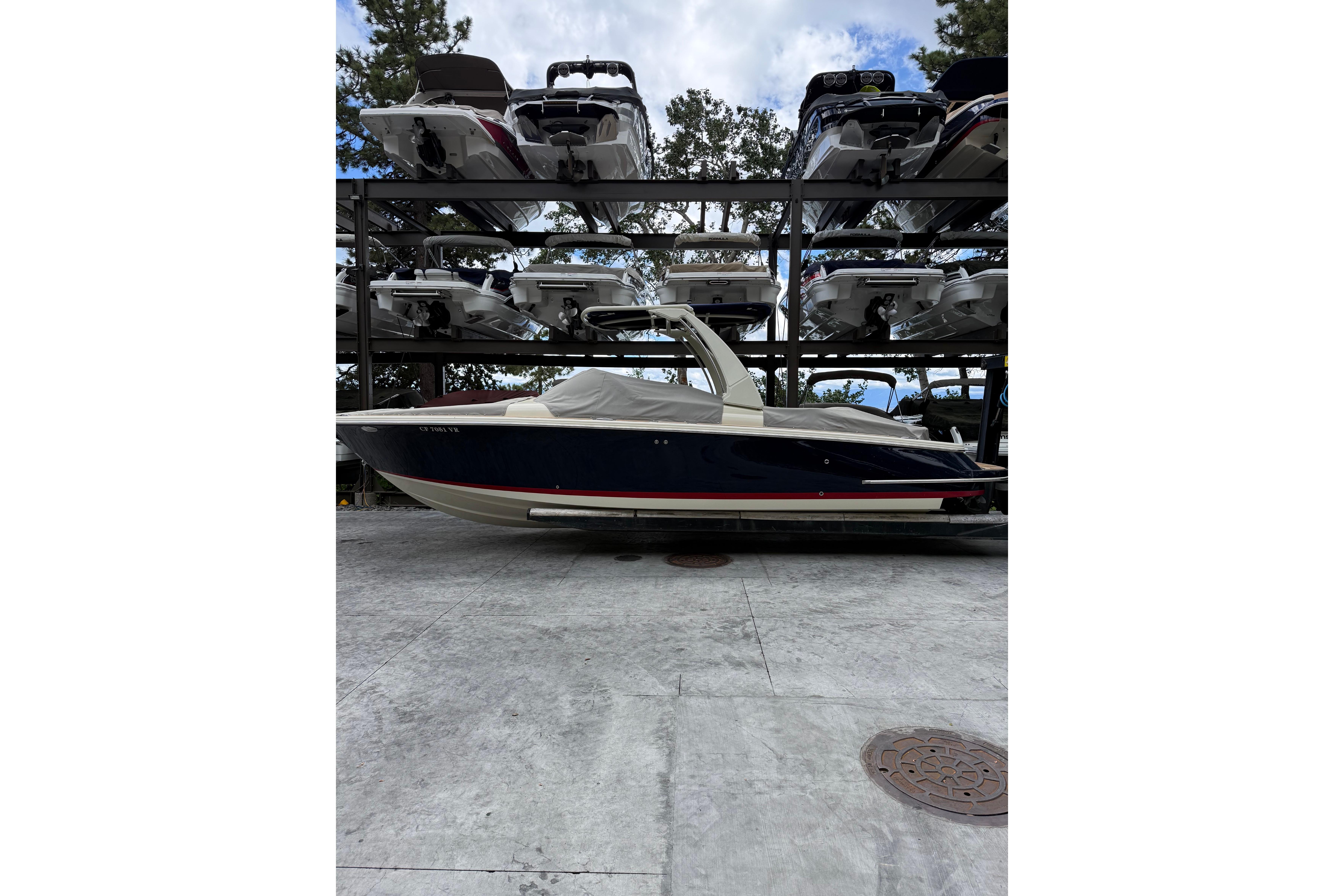 2019 Chris-Craft Launch 28 GT boat in storage, side view, covered, with stacked boats above.