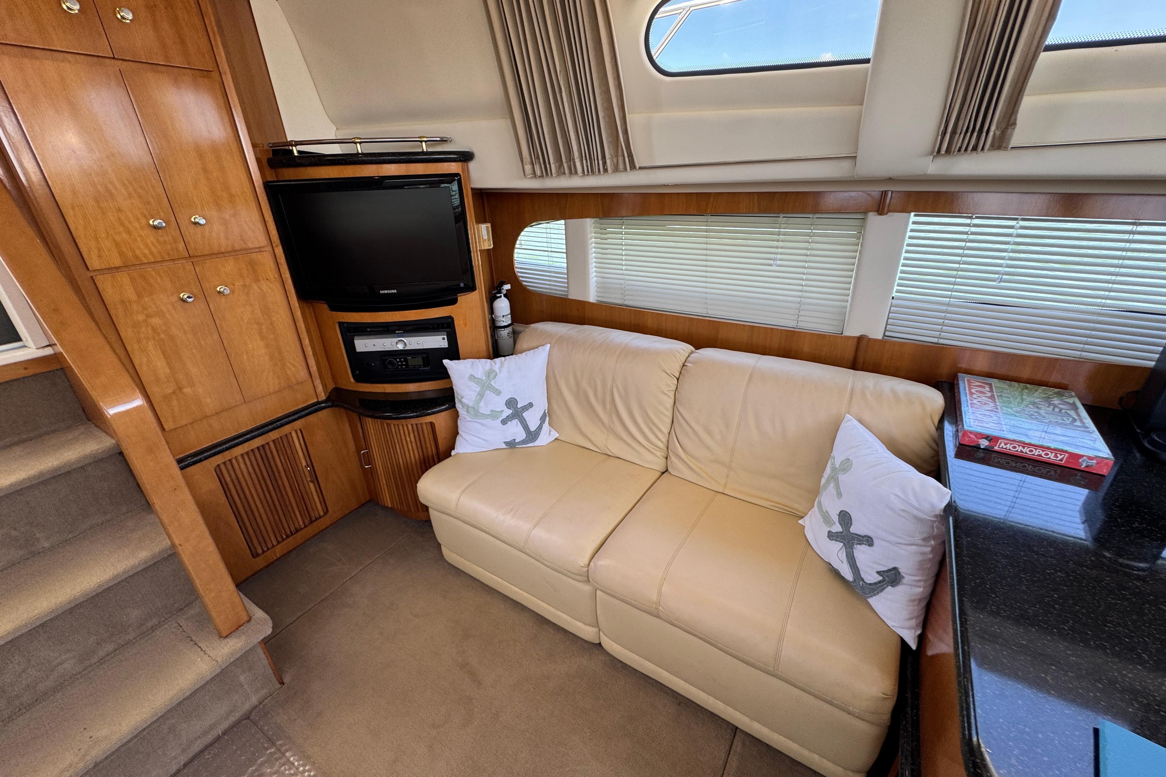 Interior of 2002 Carver 396 Motor Yacht with beige sofa, TV, and Monopoly game.