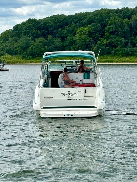 A 1992 Sea Ray 290 Sundancer on calm water with two people on board.