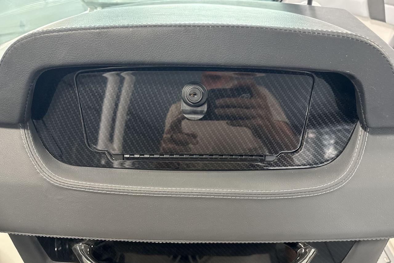 Close-up of a dashboard with carbon fiber trim and a camera.