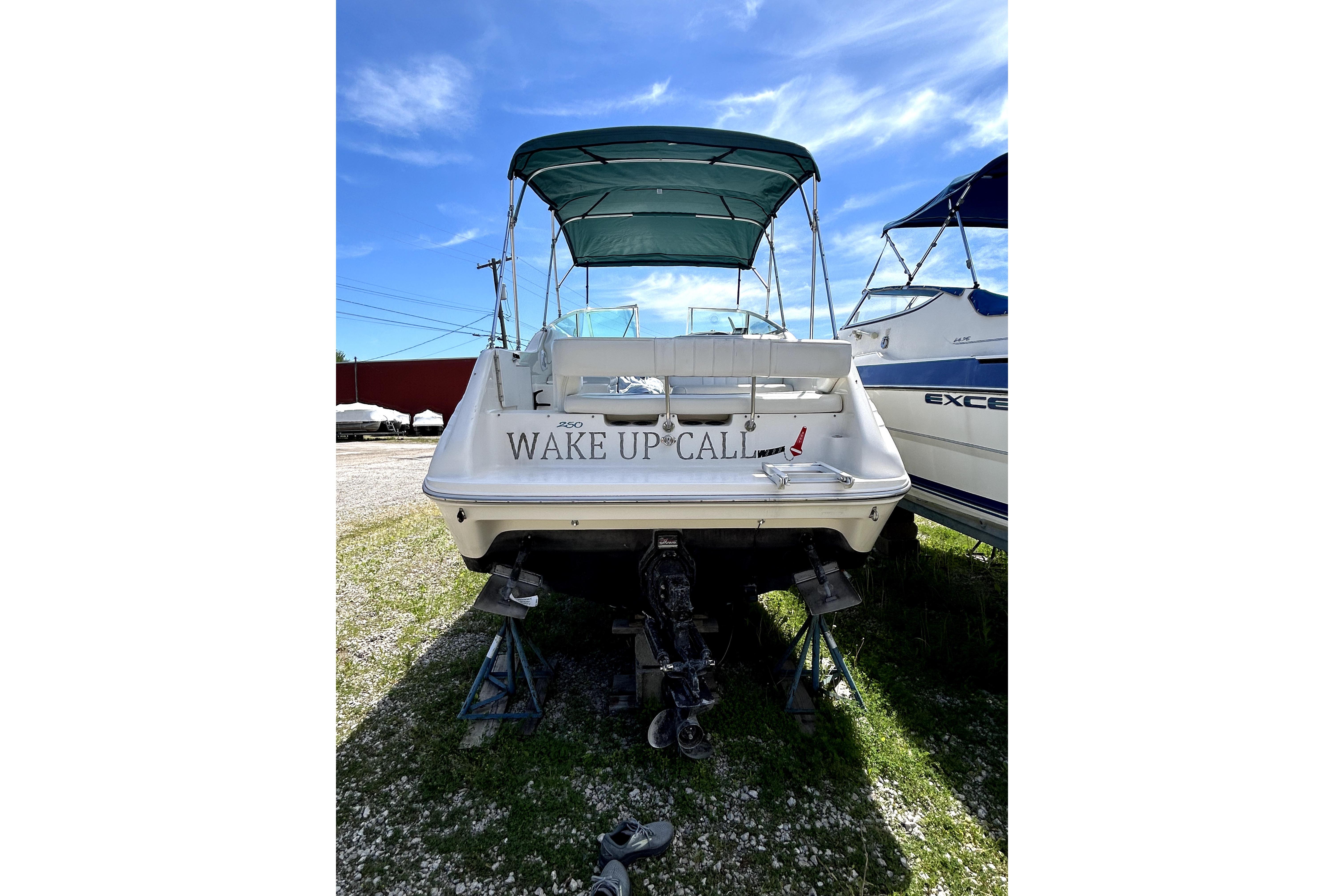 1995 Sea Ray 250 Sundancer boat with "Wake Up Call" name, docked under blue sky.