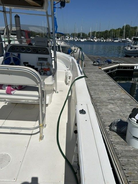 A 2000 Aquasport Osprey 250 is docked. It's a sunny day with boats in the background.