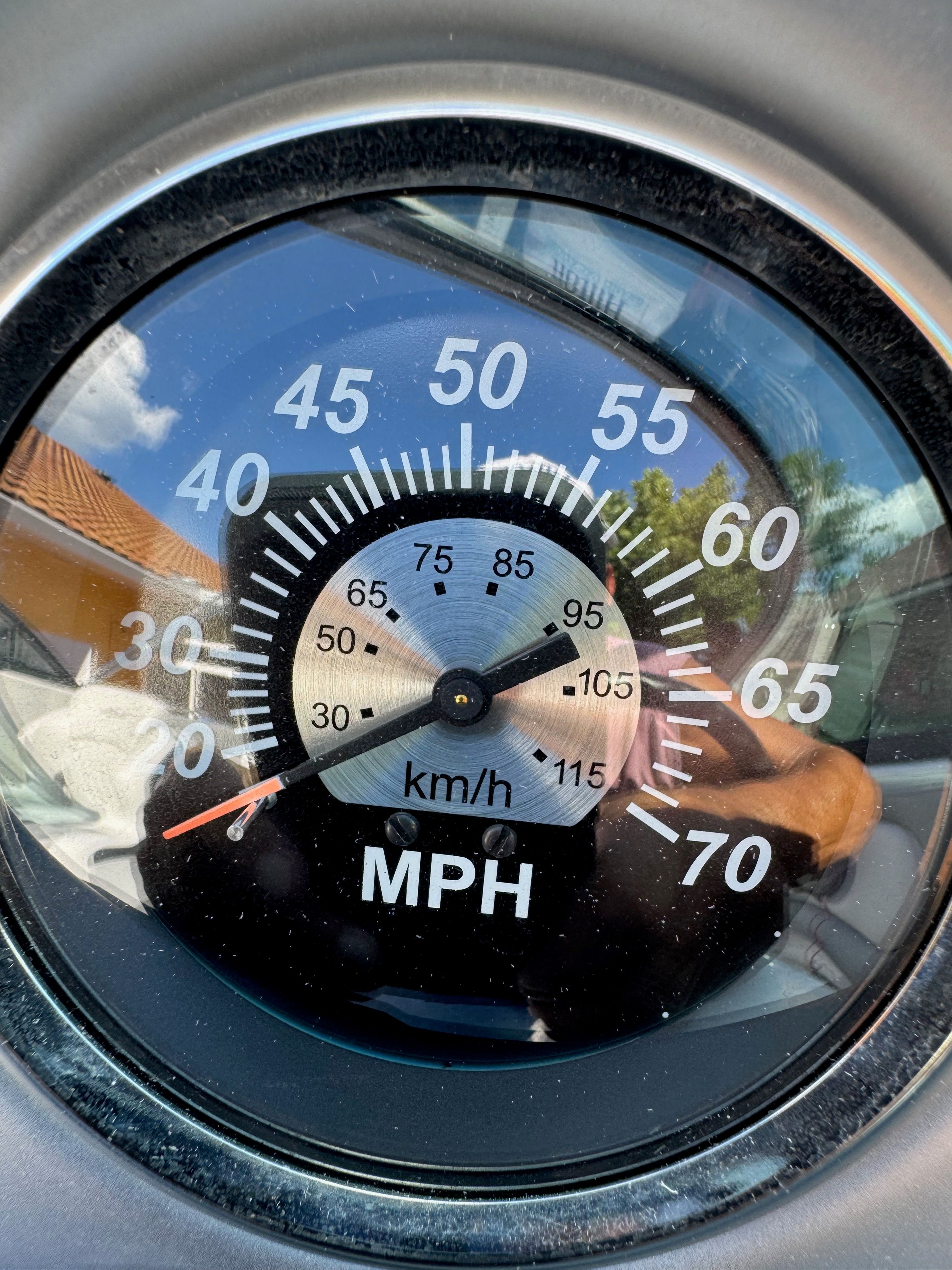 Close-up of a speedometer showing MPH and km/h, surrounded by a silver frame.