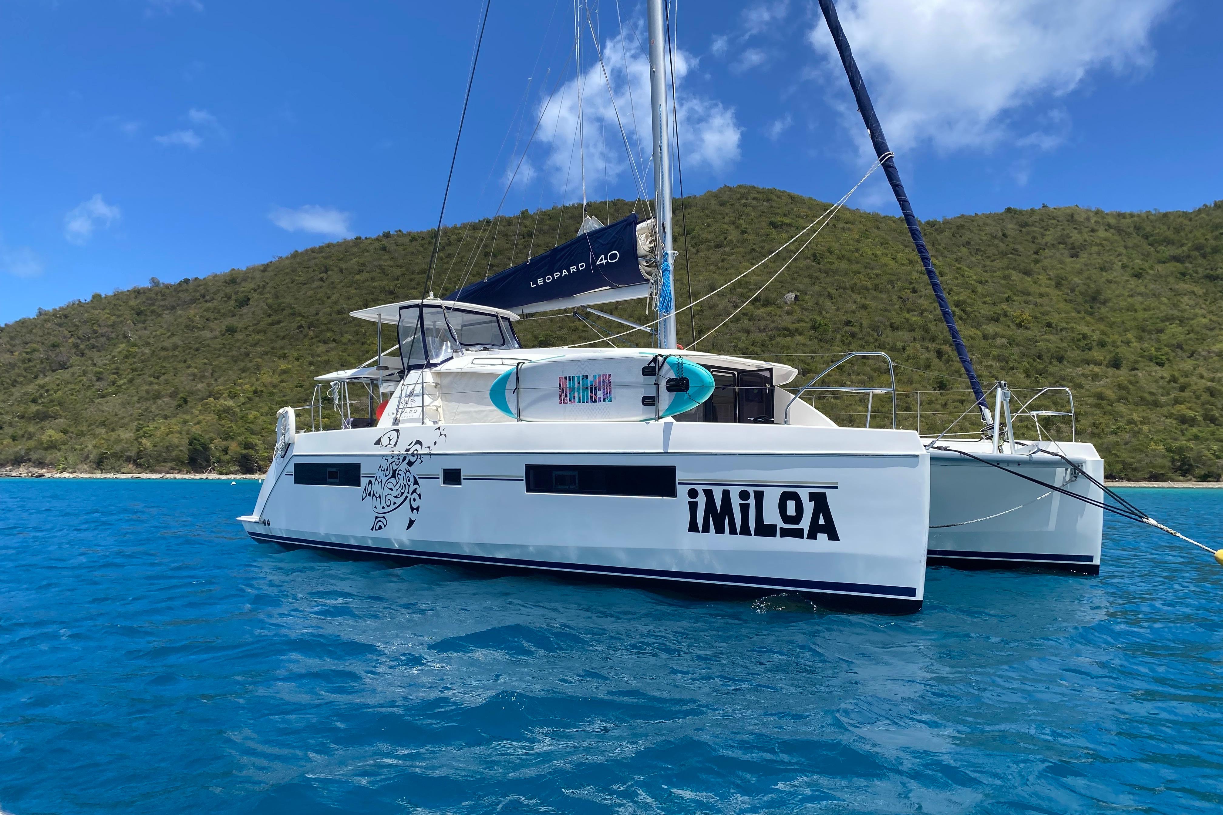 2017 Leopard 40 catamaran sailing in clear blue waters near a lush green island.