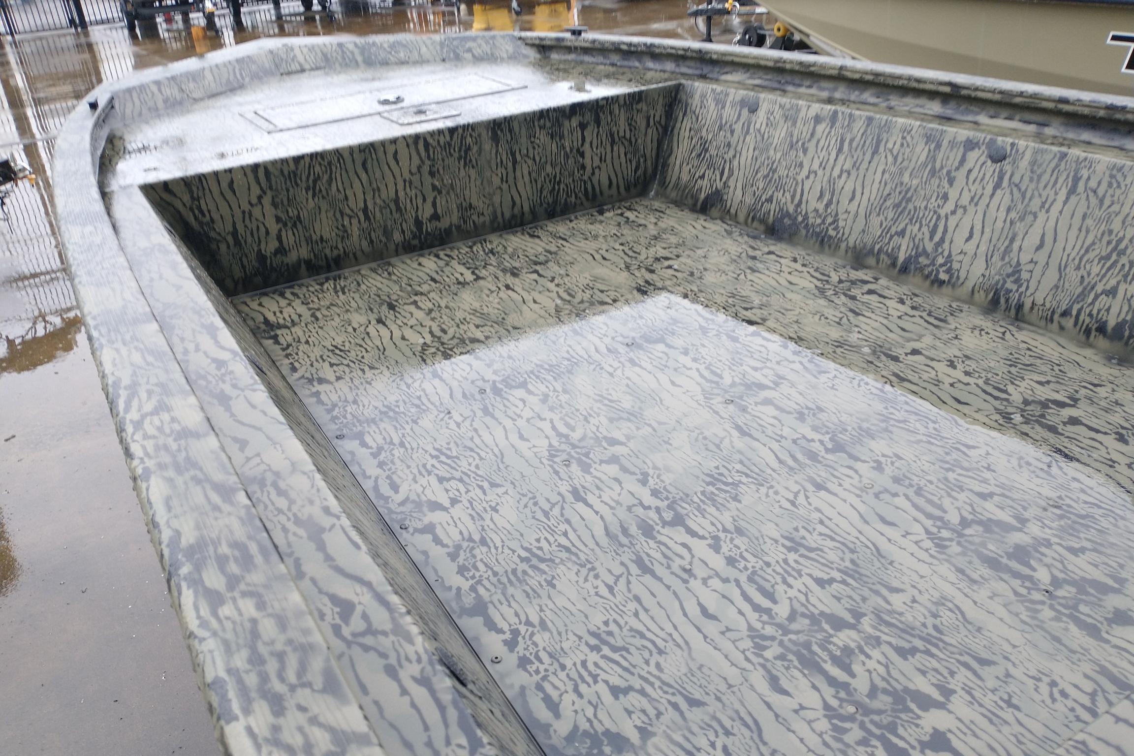 2026 Tracker Grizzly 1648 Utility boat interior with camouflage pattern, wet from rain.