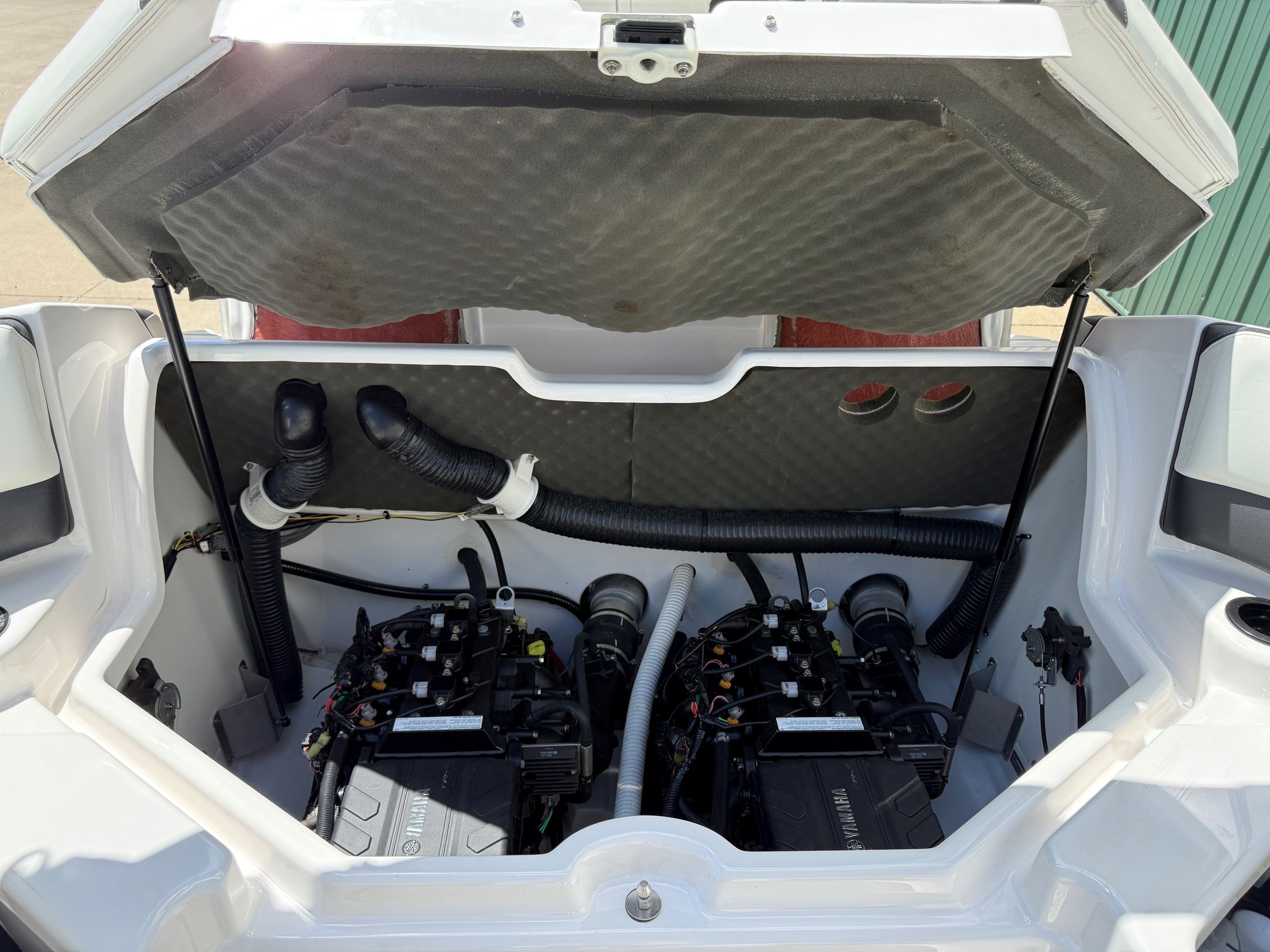 Engine compartment of a Yamaha SX210 boat with two engines and hoses.
