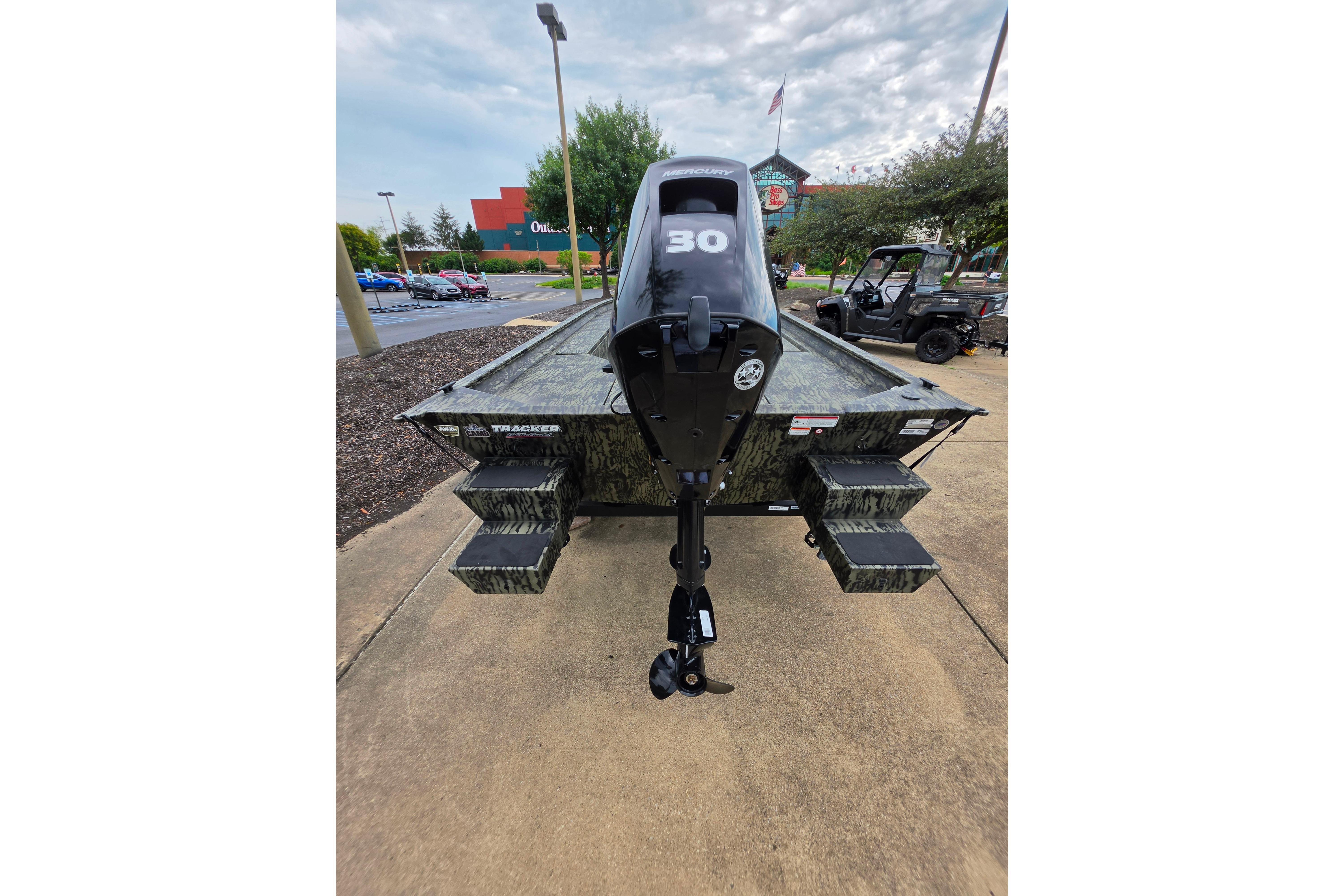 2026 Tracker Grizzly 1654 T Sportsman boat with 30 HP motor, parked outdoors.