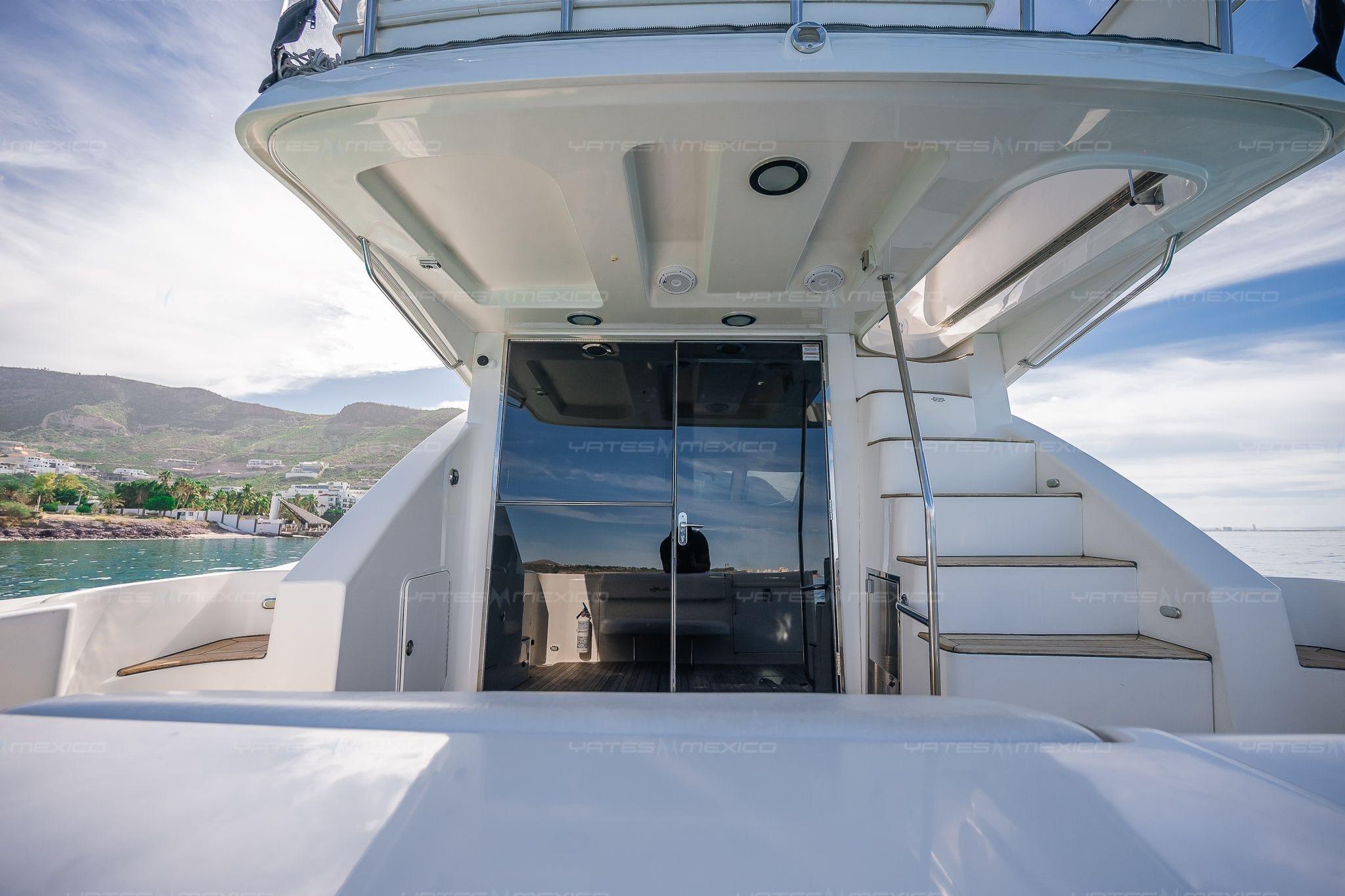 2008 Sea Ray 480 Sedan Bridge yacht with stairs and glass doors, coastal backdrop.