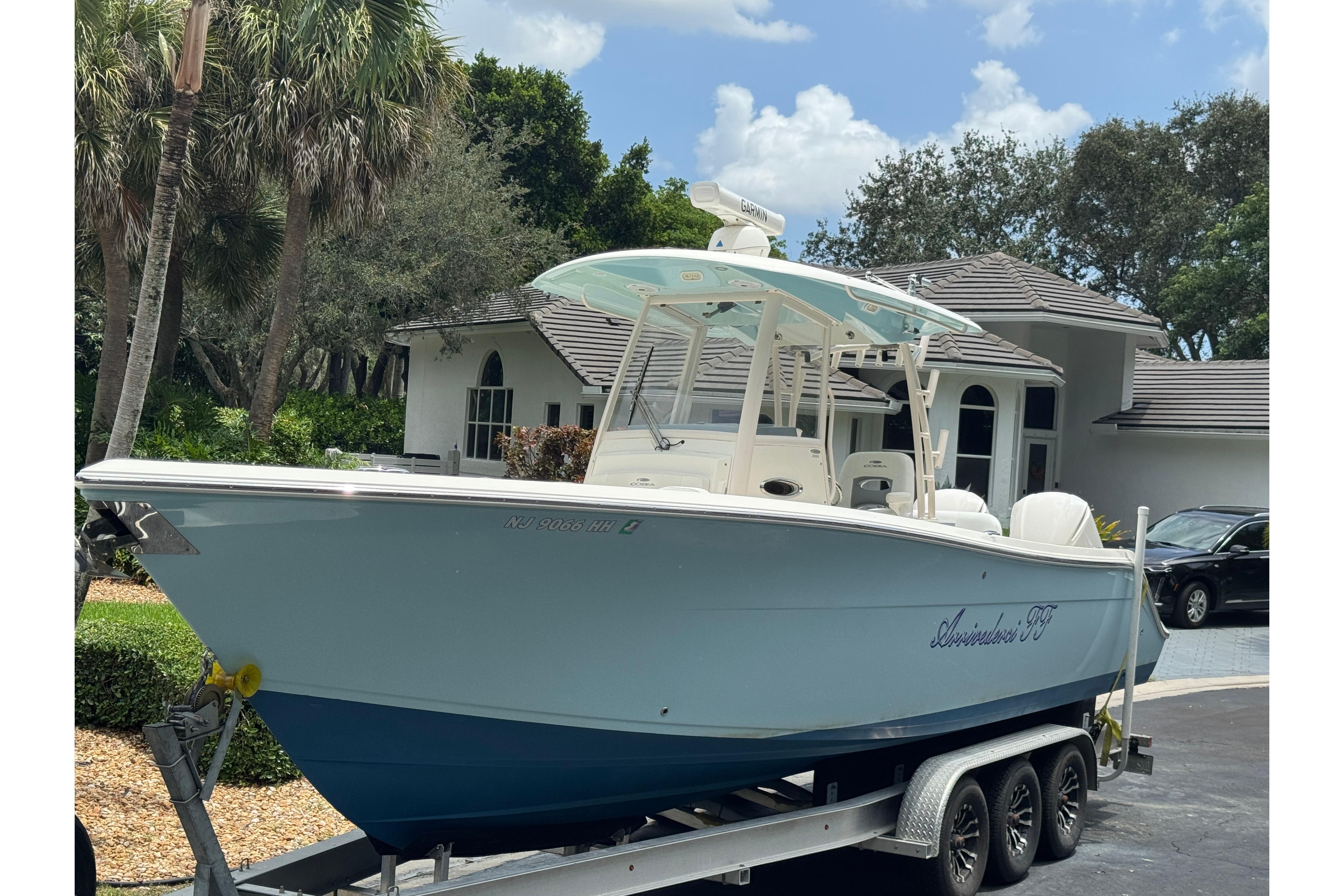 2018 Cobia 301 Center Console boat on trailer, parked in residential driveway.