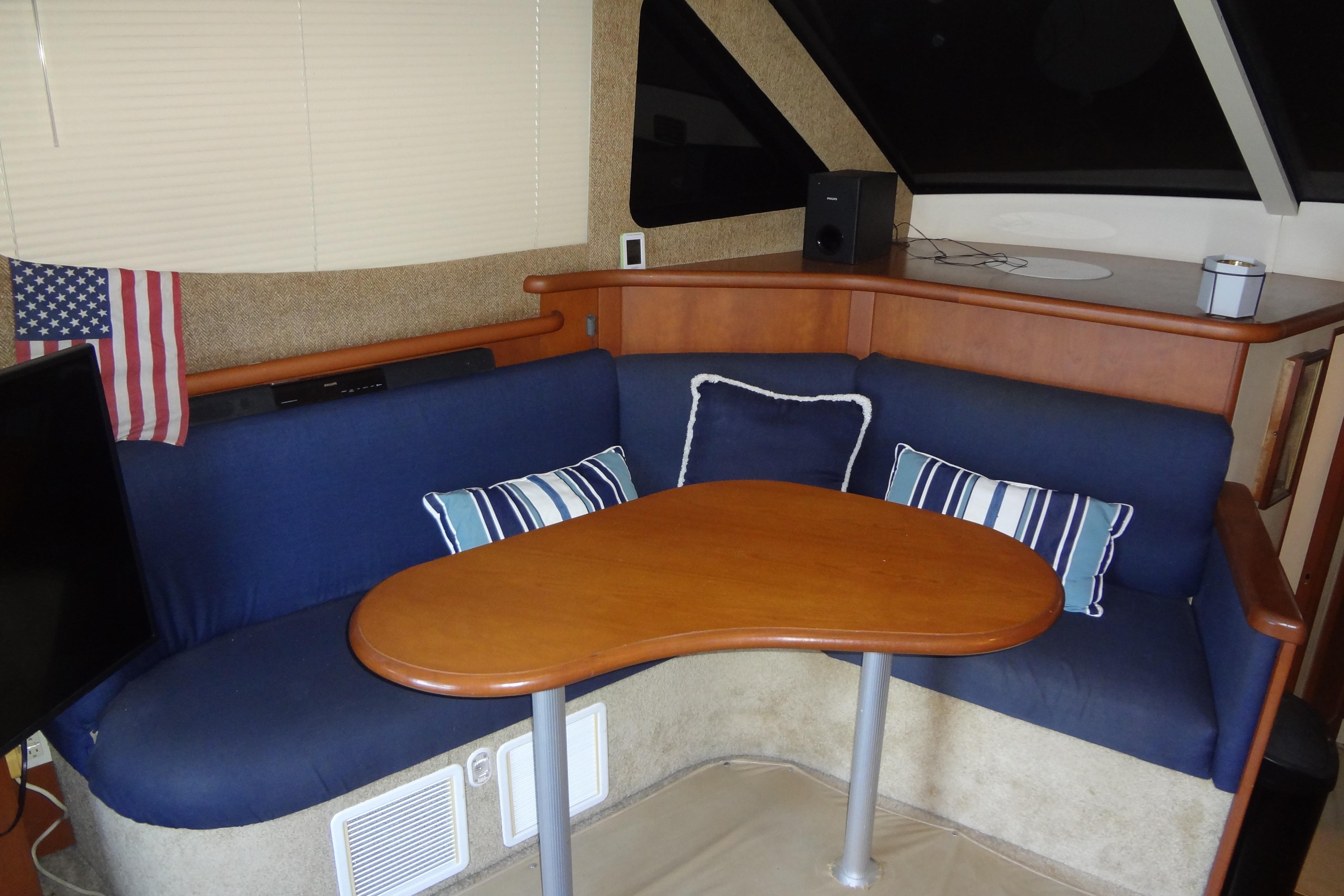 Interior of 2005 Silverton 34 Convertible yacht with blue seating and wooden table.