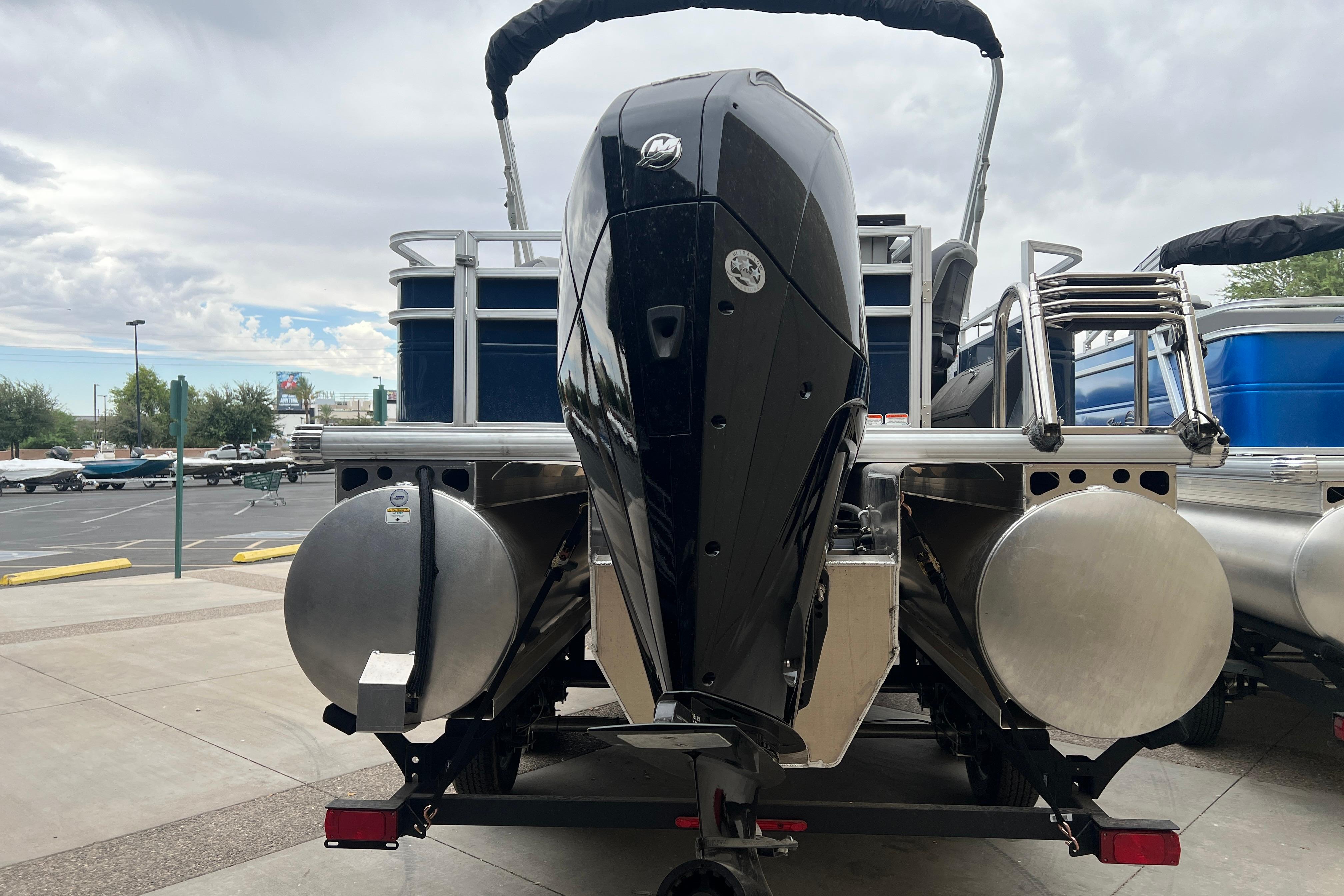 2026 Sun Tracker Sportfish 24 XP3 pontoon boat with powerful outboard motor, parked outdoors.