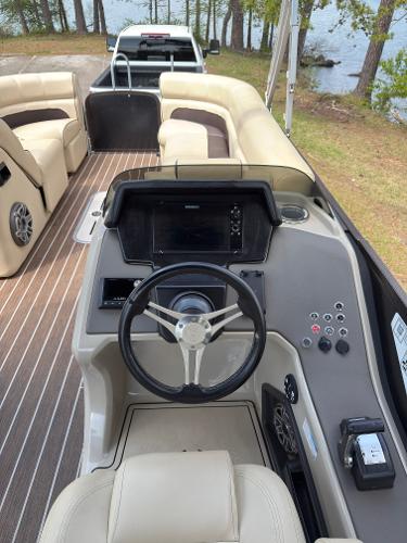 2022 Premier 250 Solaris boat interior with steering console and seating, near a lake.