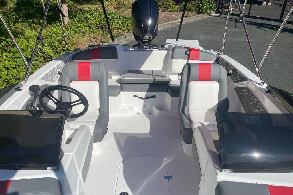 2026 Tahoe T21 boat interior with modern seating and steering wheel, featuring red and gray accents.