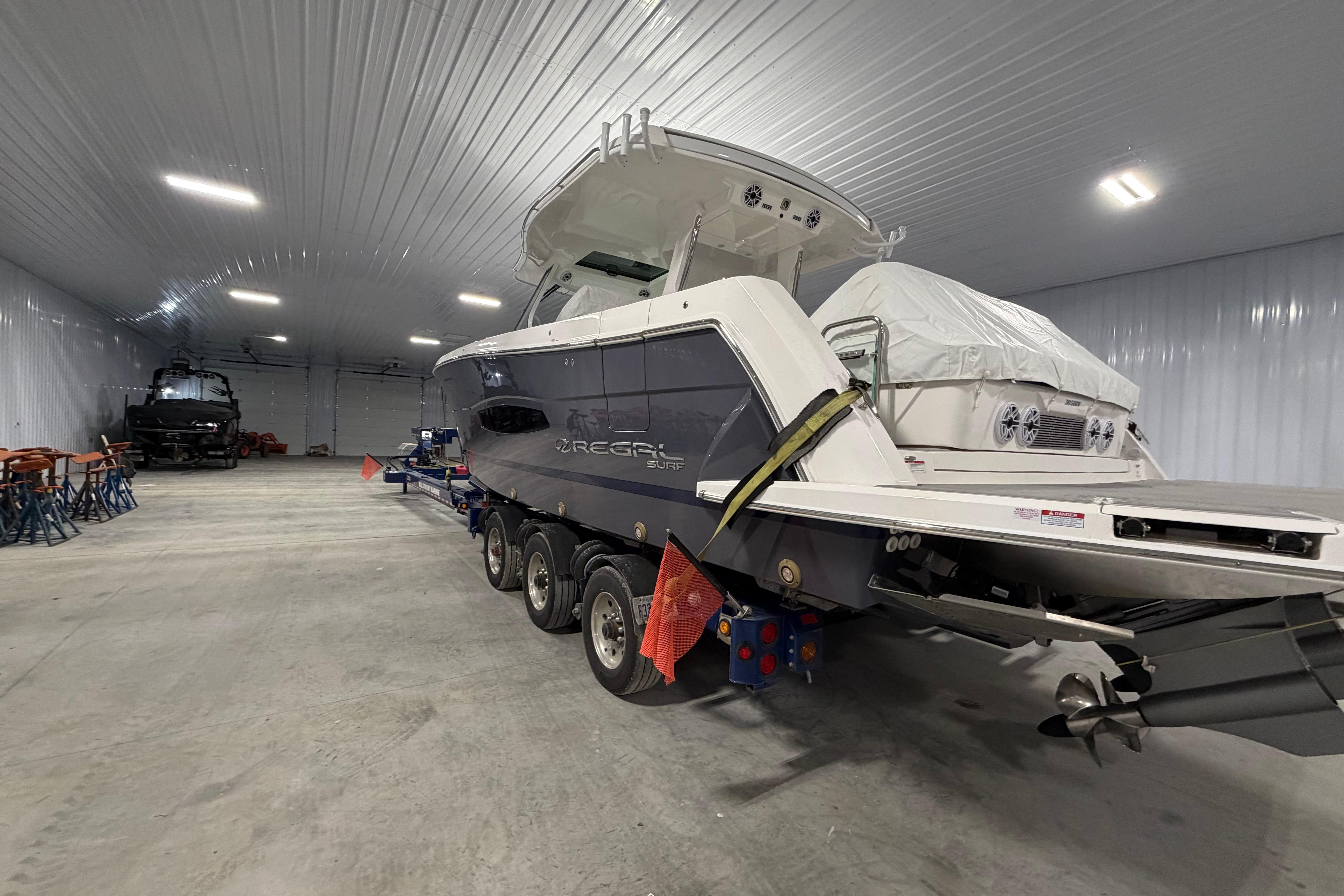 2027 Regal 38 Surf boat in a spacious indoor storage facility.