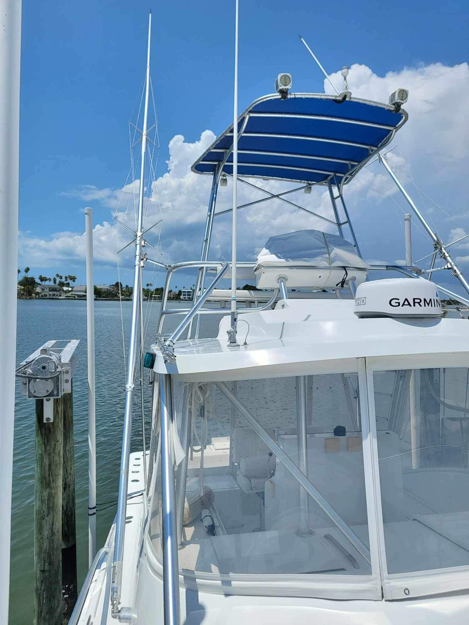 1997 Luhrs 32 Open boat docked, featuring a blue canopy and Garmin equipment.