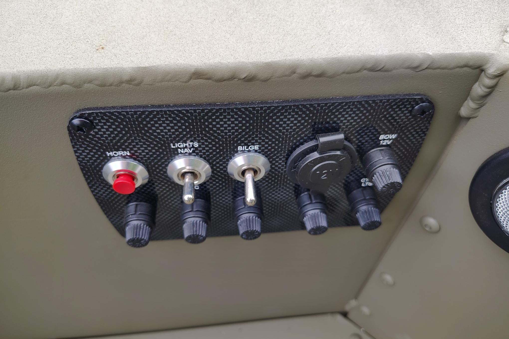 Control panel of 2026 Tracker Grizzly 1654 T Sportsman boat with switches and knobs.