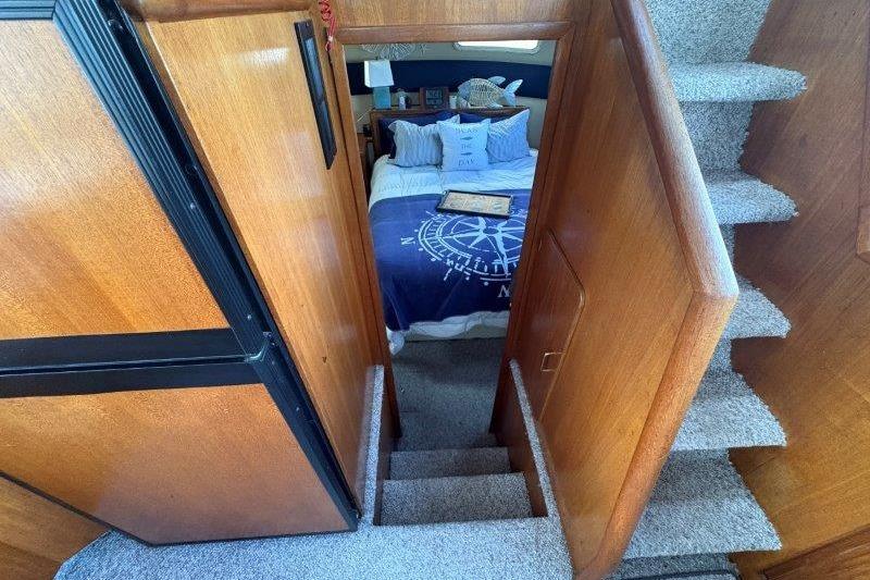 Interior of 1987 Tollycraft 34 Sundeck Motor Yacht with cozy bedroom and wooden stairs.