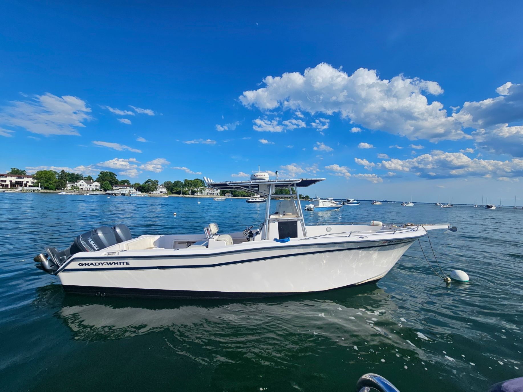 A 1997 Grady-White Chase 263 boat floats on calm water under a clear blue sky.