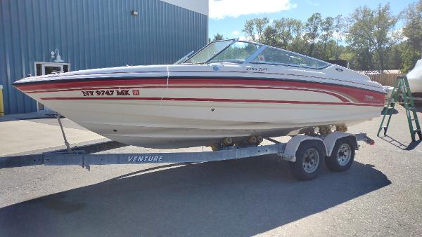 1999 Chaparral 2130 SS boat on trailer, parked outdoors near a blue building.