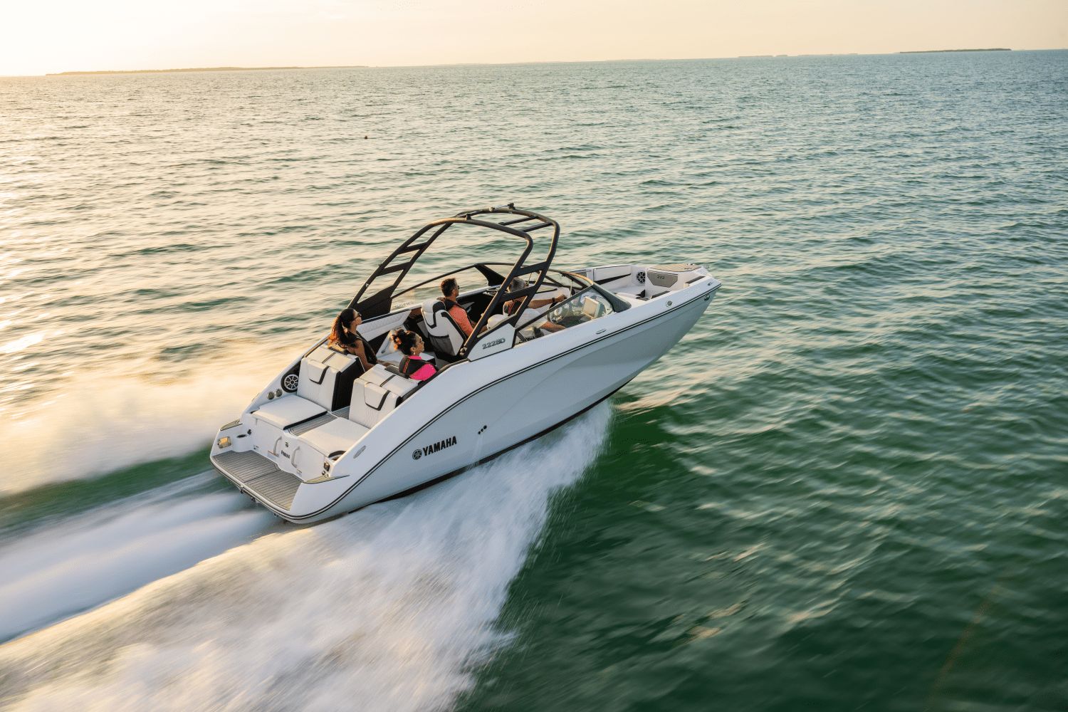 A Yamaha 222SD boat speeds across the water at sunset.