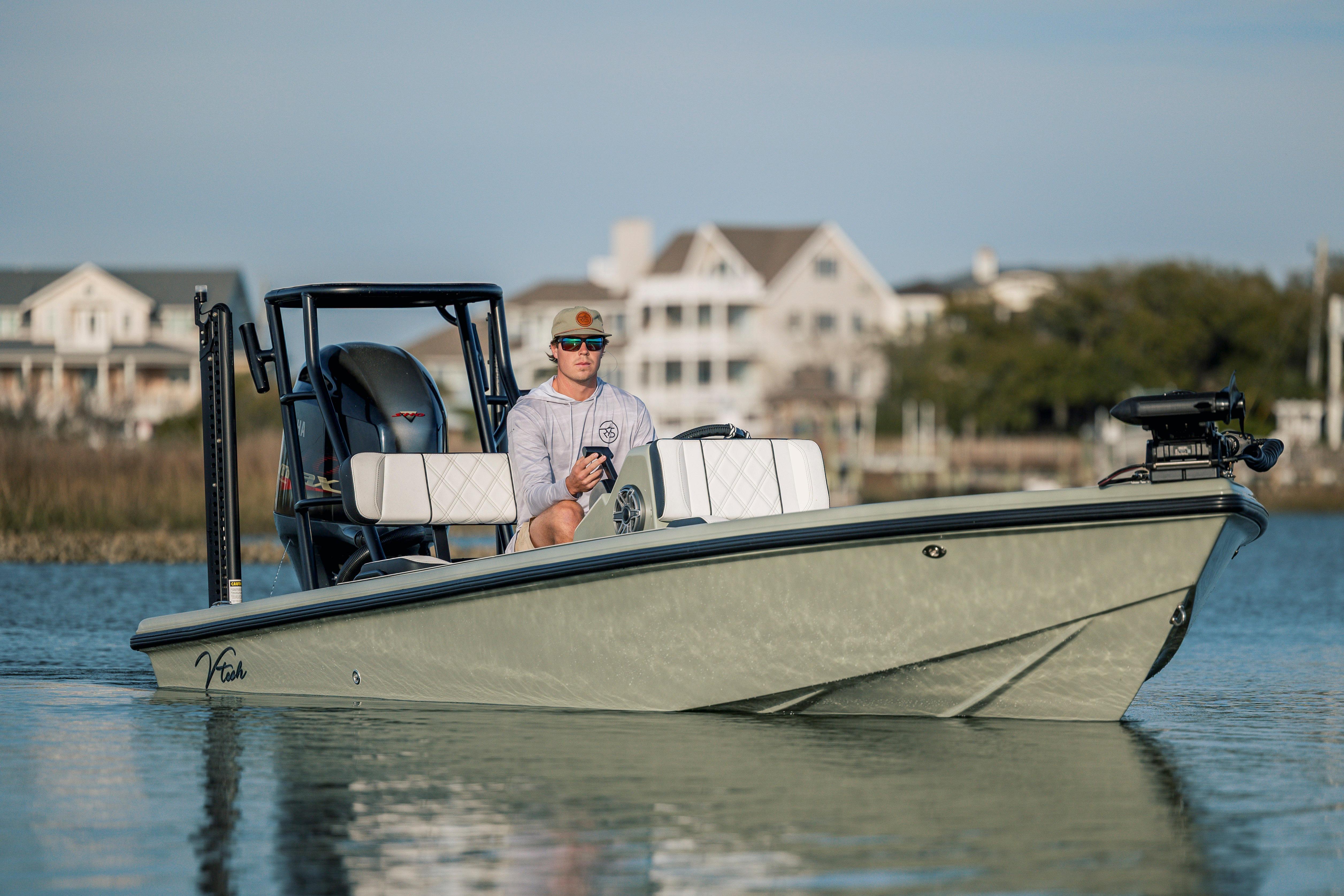 Man on Vtech 18 boat, 2025 model, cruising near coastal homes.