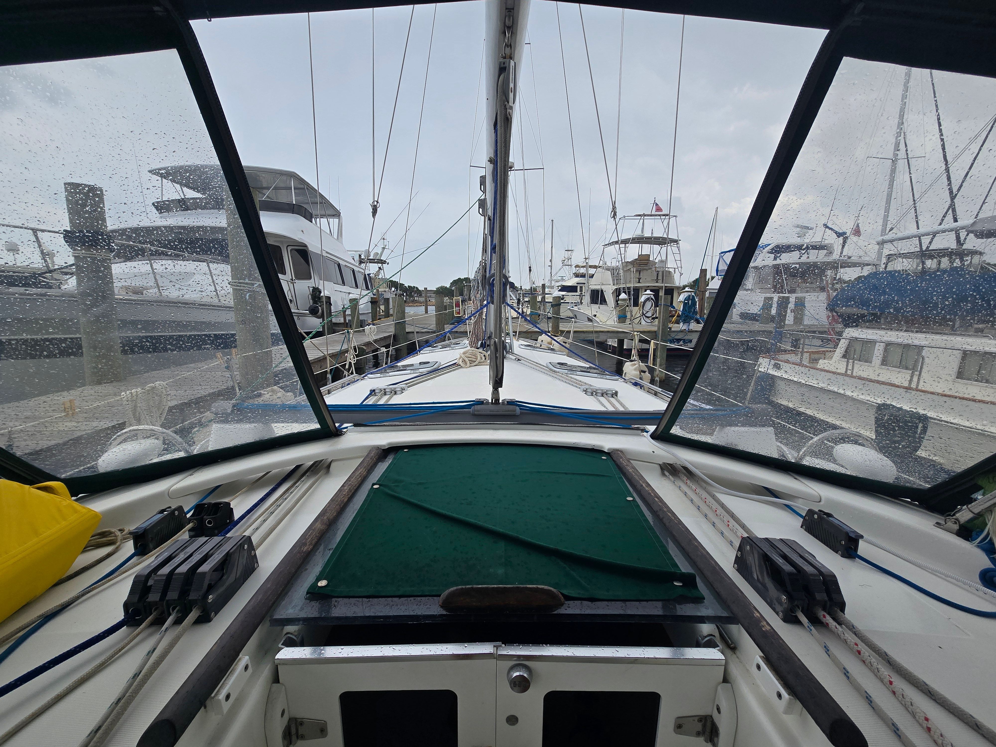 The cockpit of a 1998 Beneteau 411, docked in a marina on a rainy day.