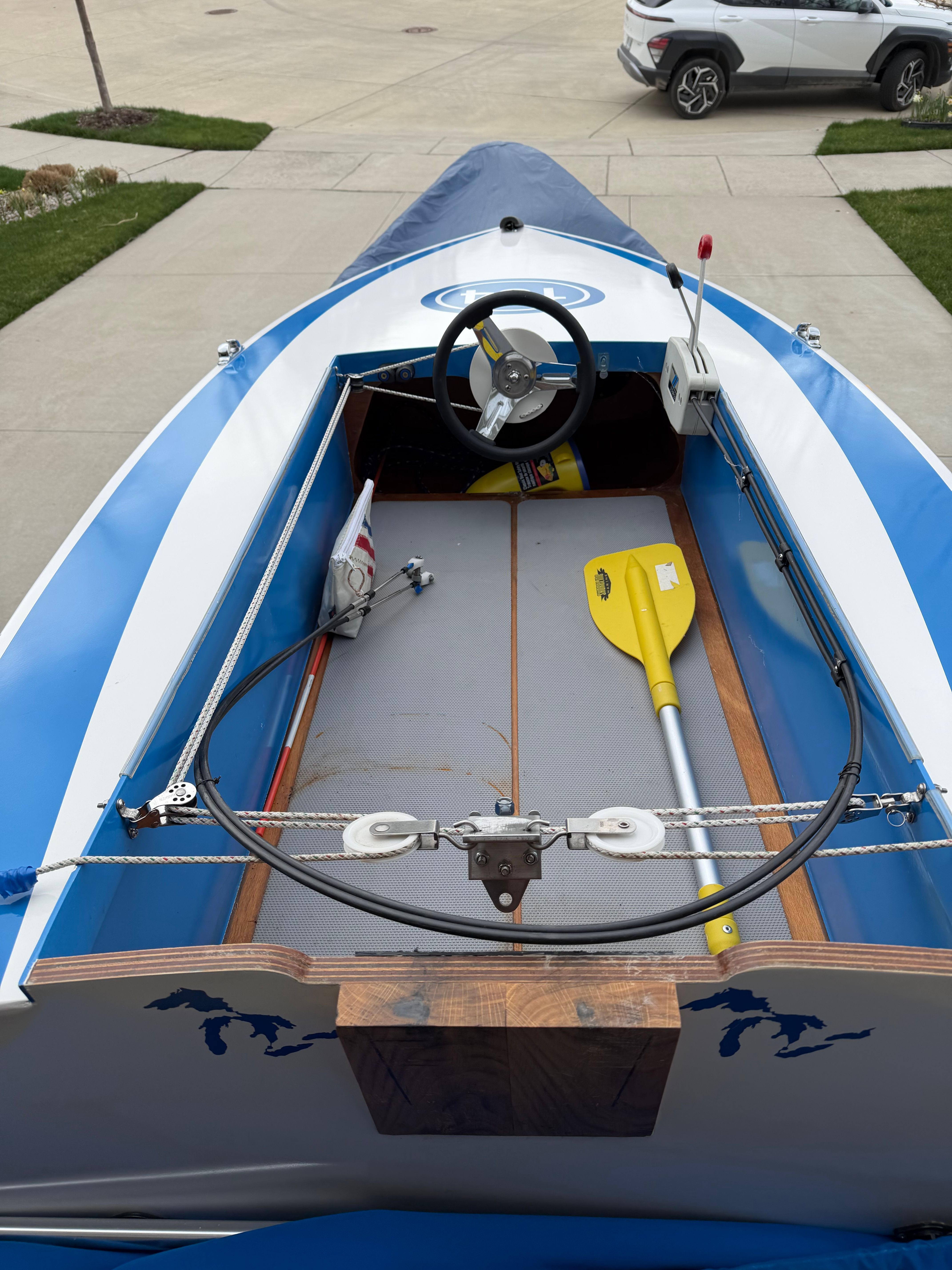 A blue and white racing boat with a steering wheel and a yellow paddle in the cockpit.