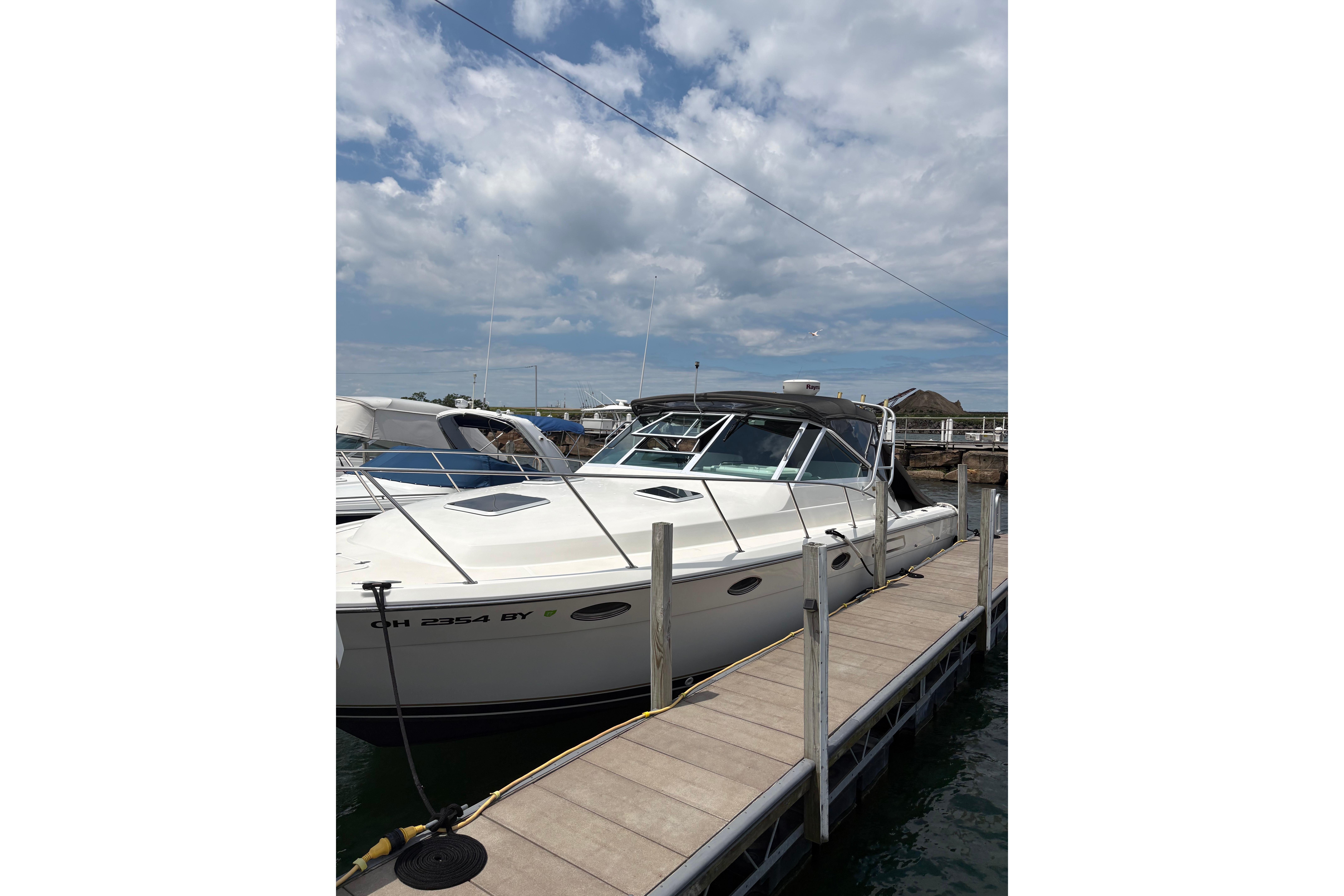 1999 Tiara Yachts 3100 Open docked under a partly cloudy sky.
