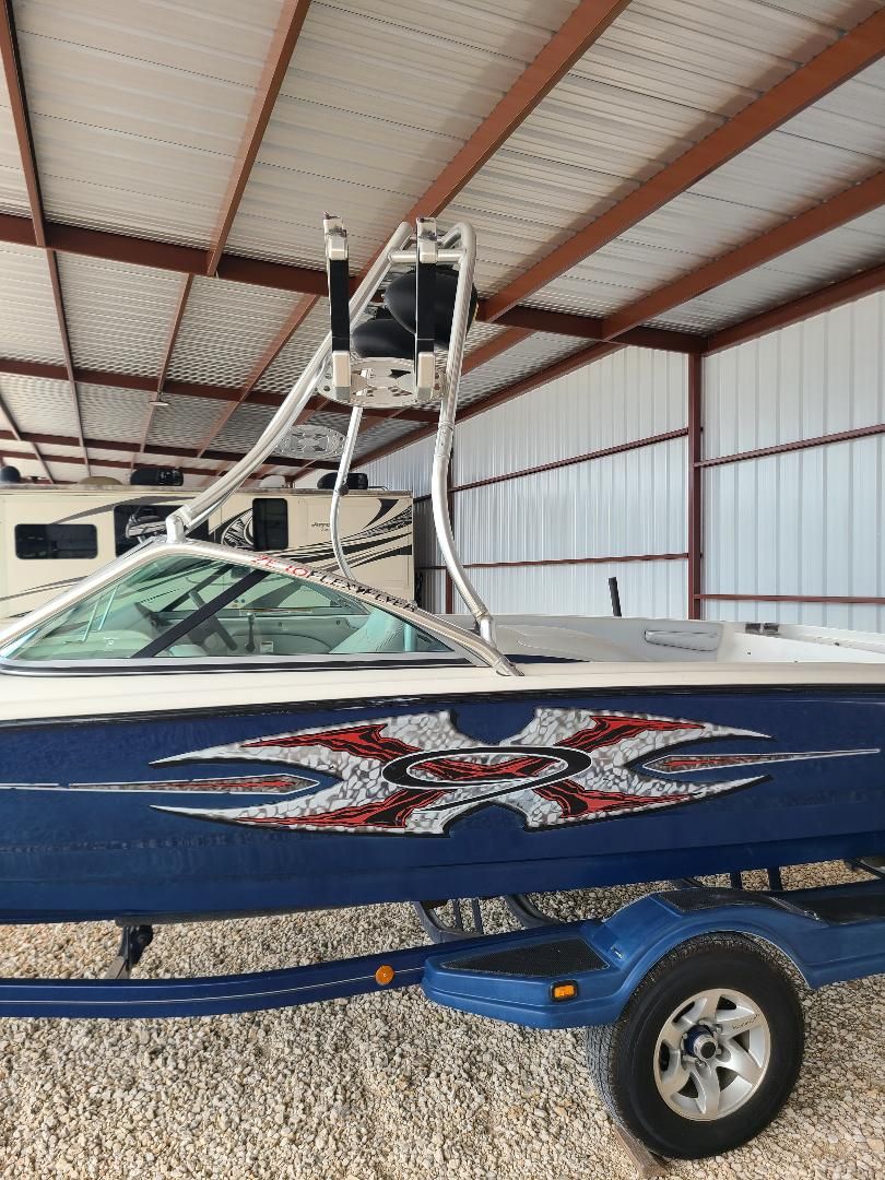 2003 MasterCraft X-9 boat in storage, featuring blue hull and custom graphics.