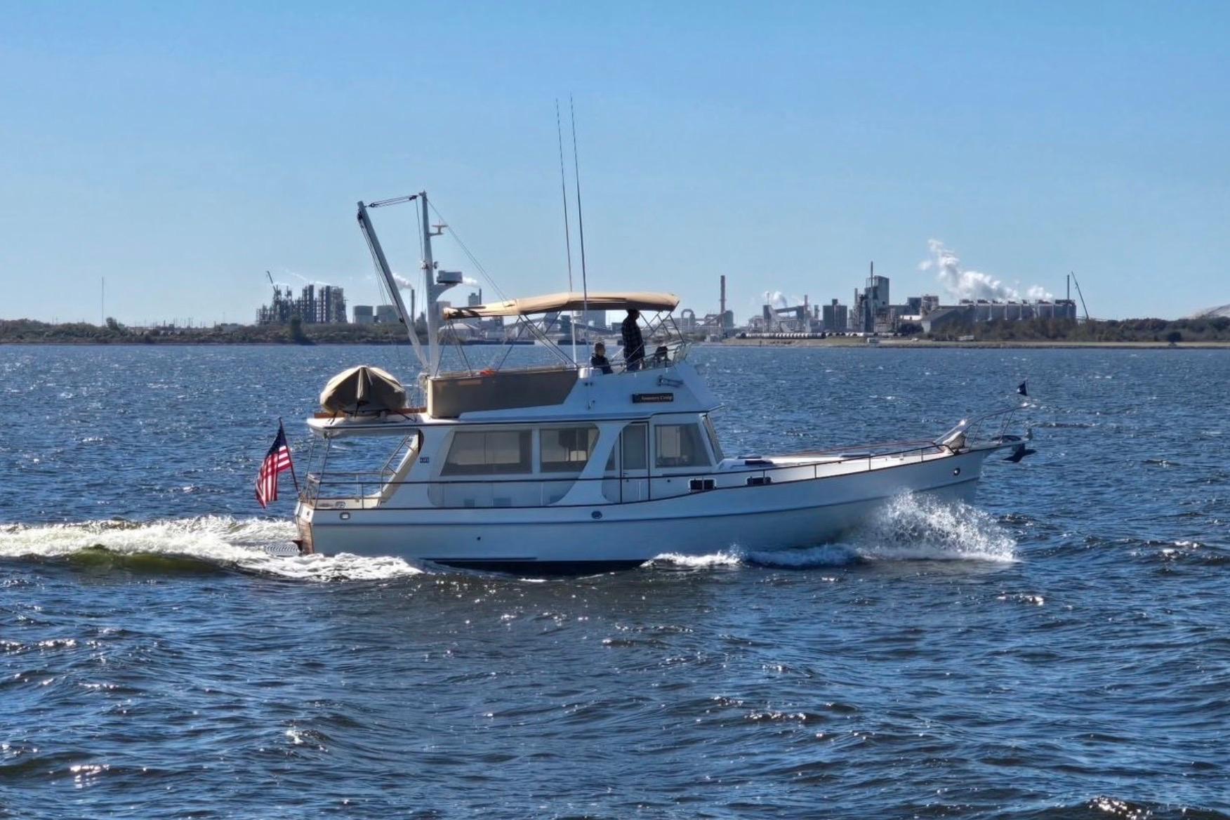 1999 Grand Banks 42 Europa cruising on open water with industrial skyline in background.