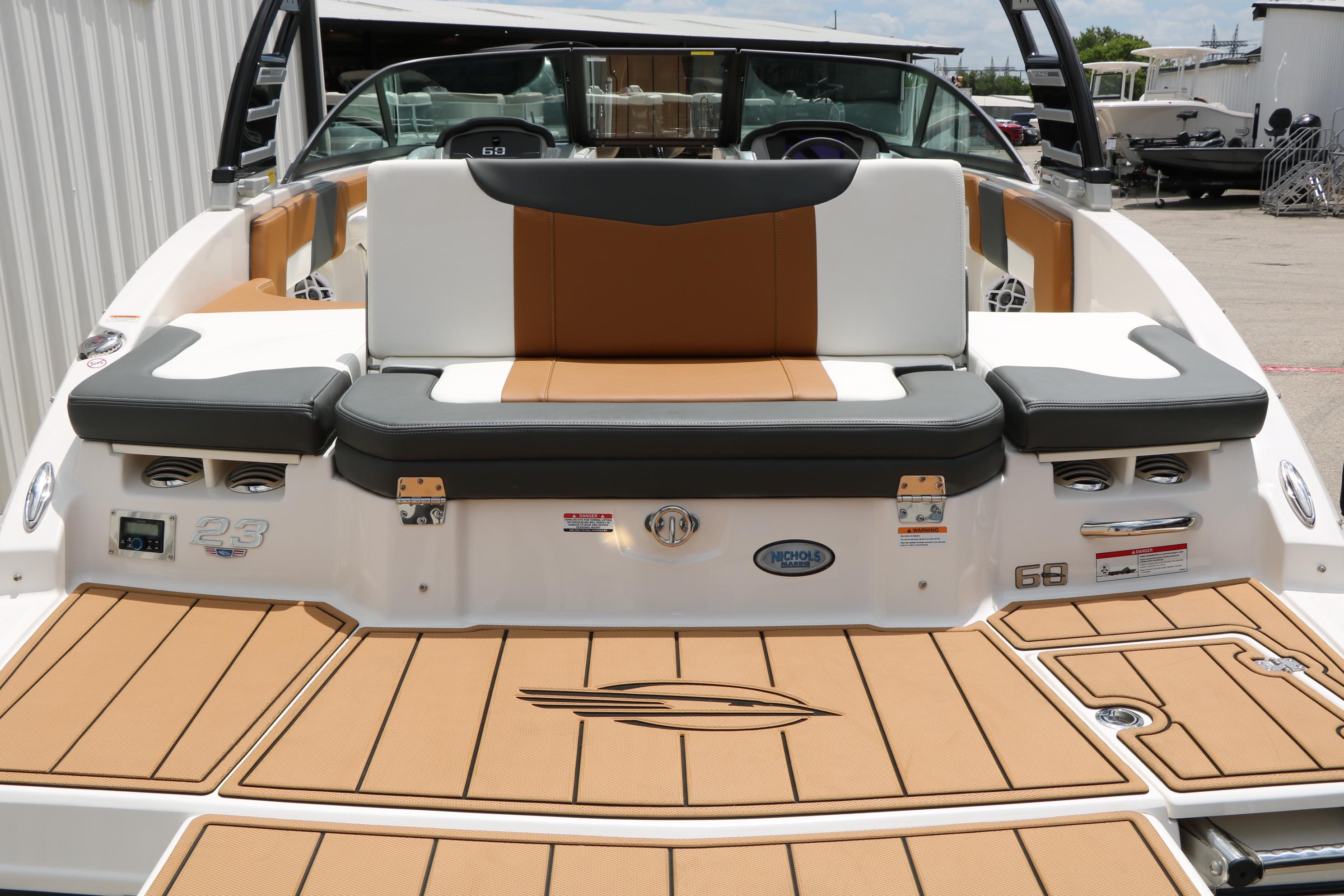2025 Chaparral 23 SSi boat with tan and gray seating, docked outdoors.