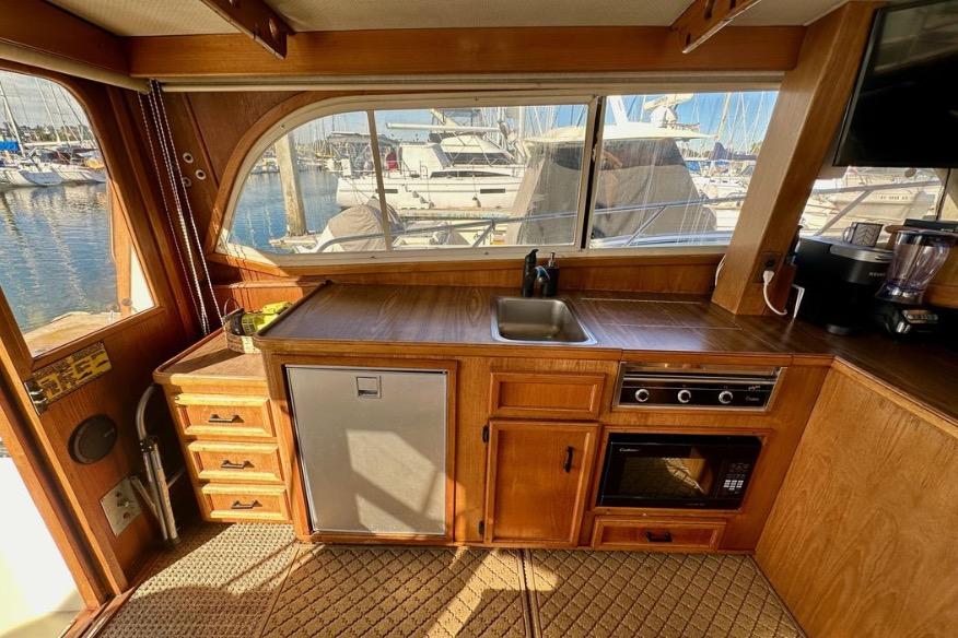 Interior of 1985 Egg Harbor 33 Sedan yacht with kitchenette and marina view.