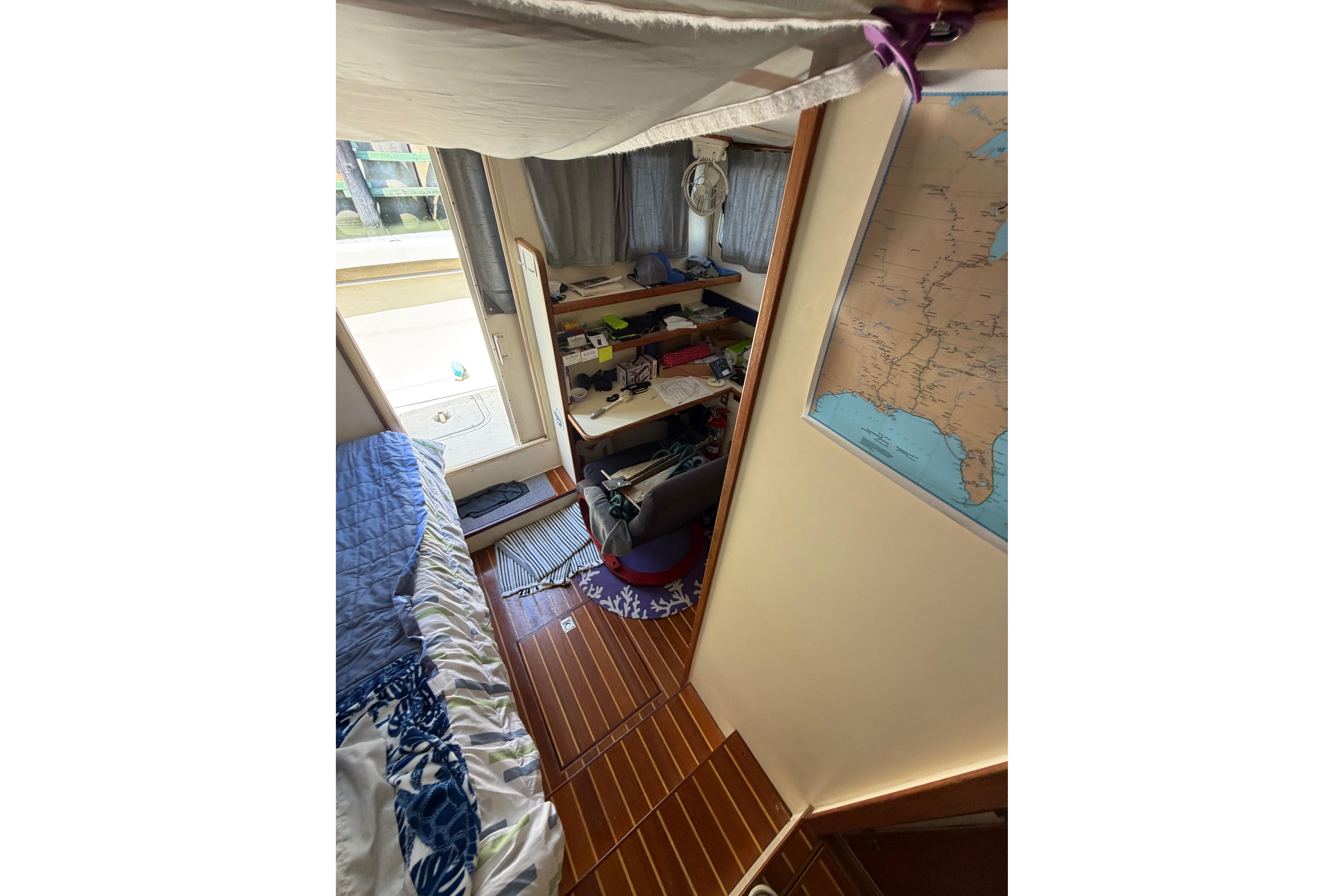 Cozy interior of a 1997 Rosborough Trawler with bed, desk, and map on wall.
