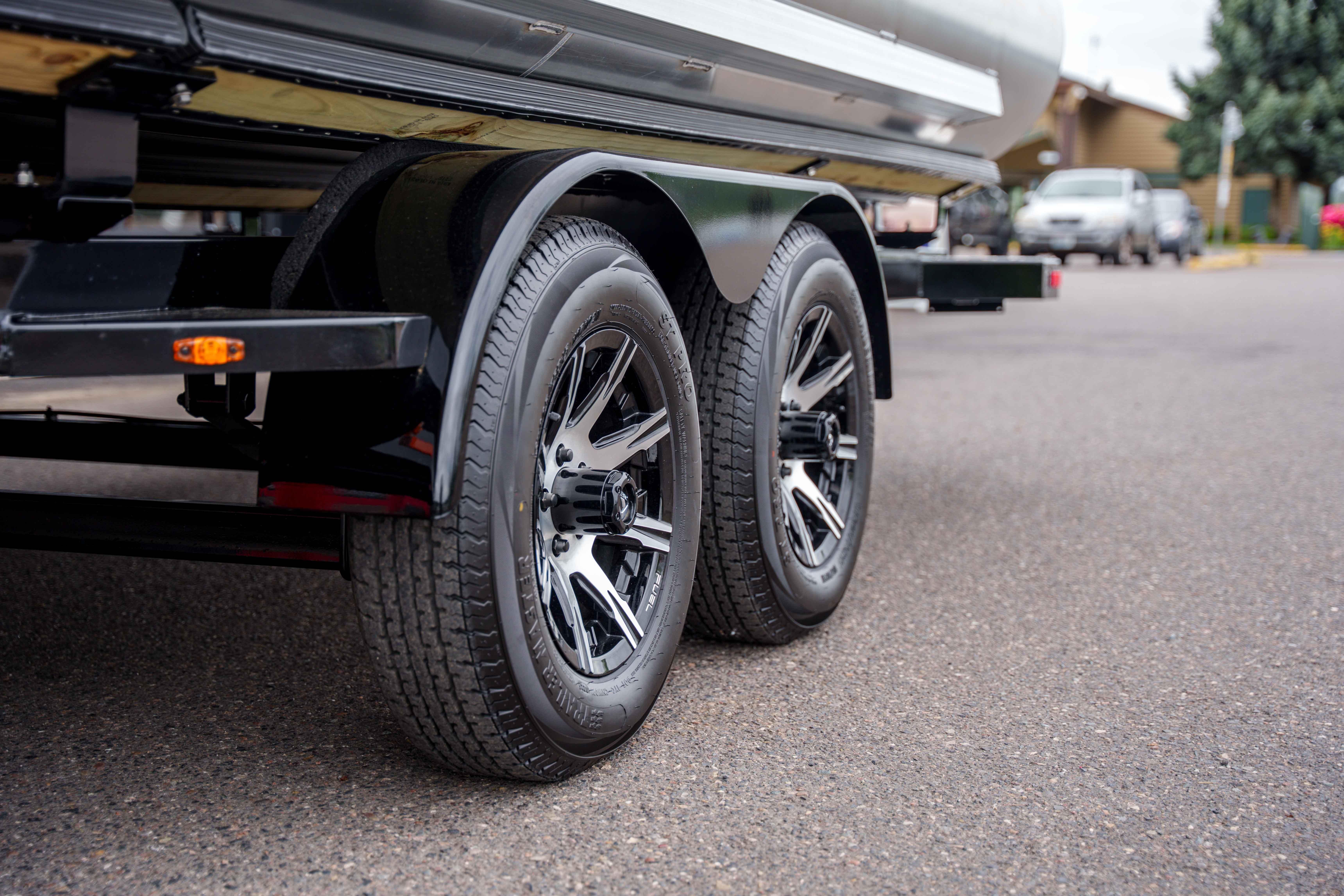 Trailer wheels of a 2026 Harris Sunliner 230 boat on pavement.