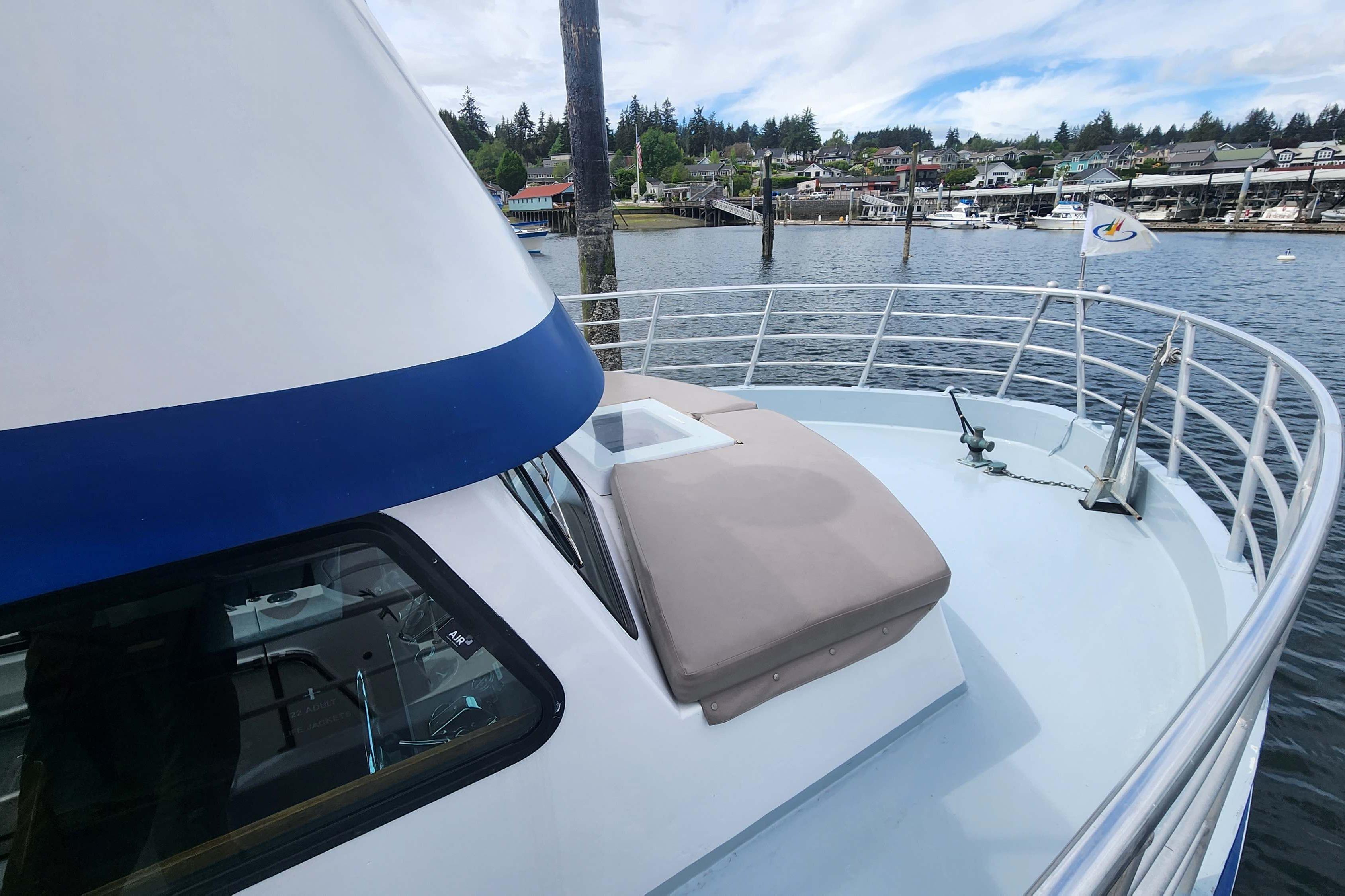 1964 Grandy Tour Boat on calm water, featuring a spacious deck and scenic harbor view.
