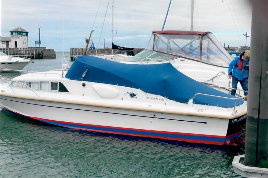 1989 Fairey Spearfish MKIII boat docked with blue cover in marina.