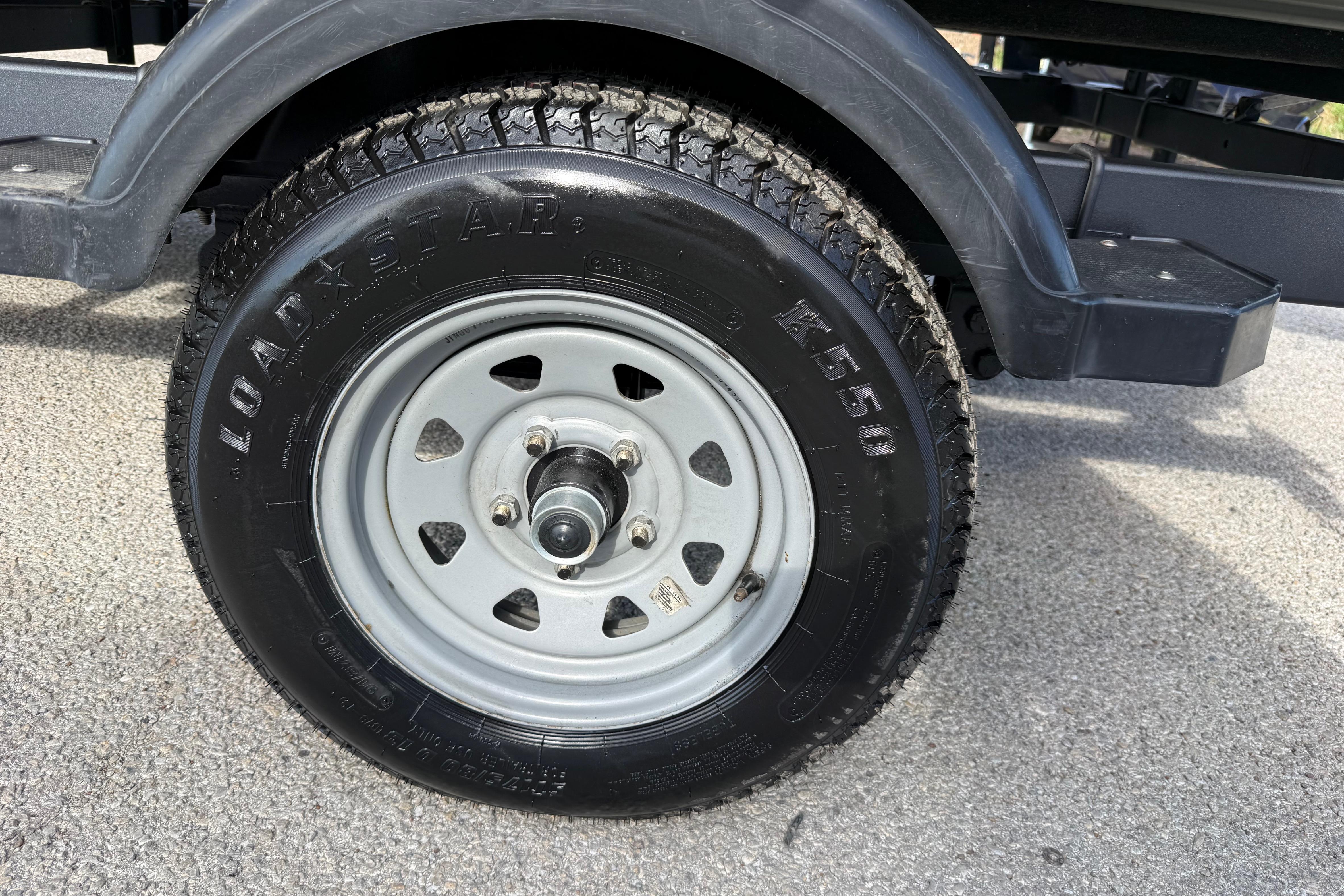 Trailer wheel of a 2020 Lowe Roughneck 2070 Big River boat on pavement.